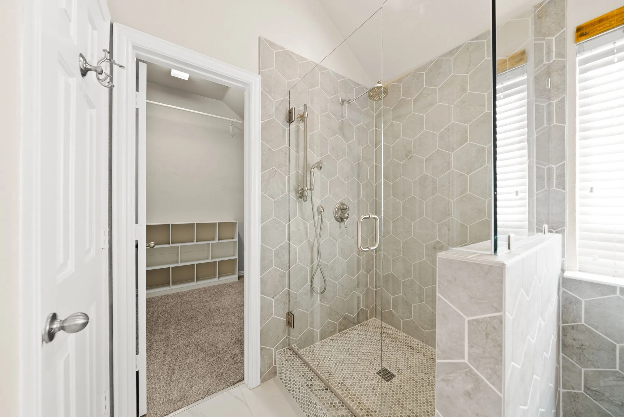 Walk-in shower with hexagonal tile surround, glass enclosure, and mosaic floor