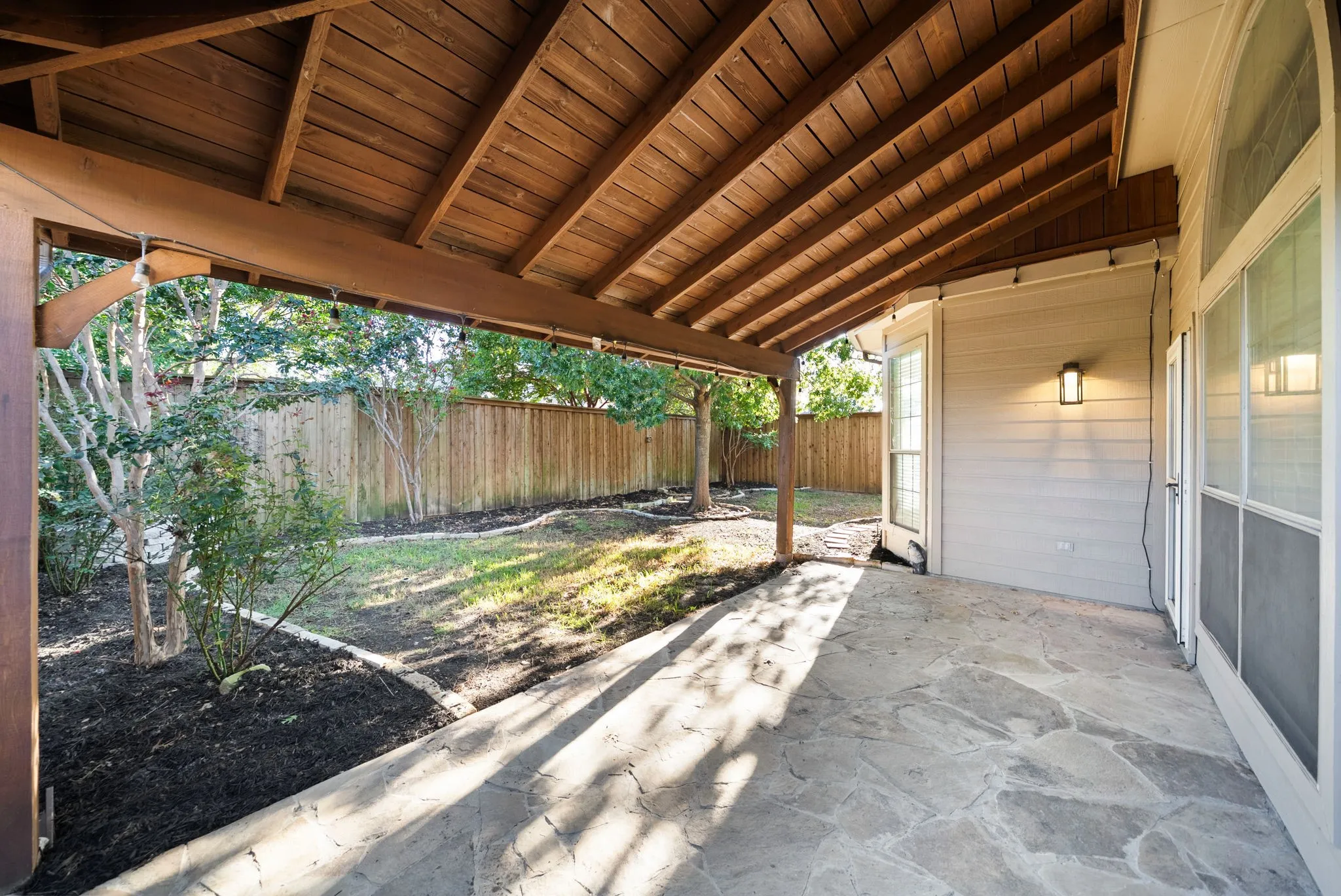 Covered patio with a natural stone-look surface, wood plank ceiling, and recessed lighting