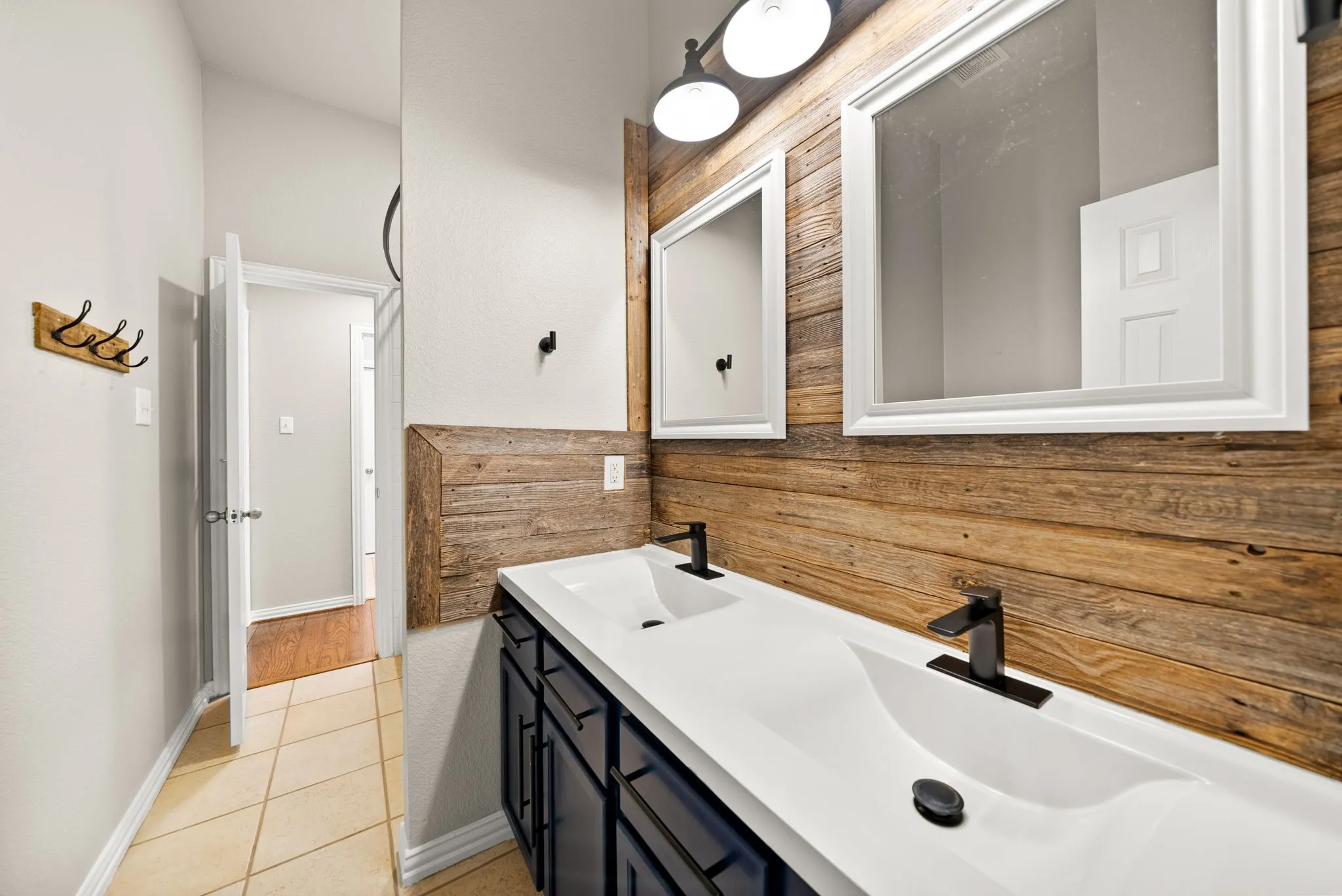 Dual vanity with integrated sinks, dark wood-finish cabinetry, and matte black fixtures