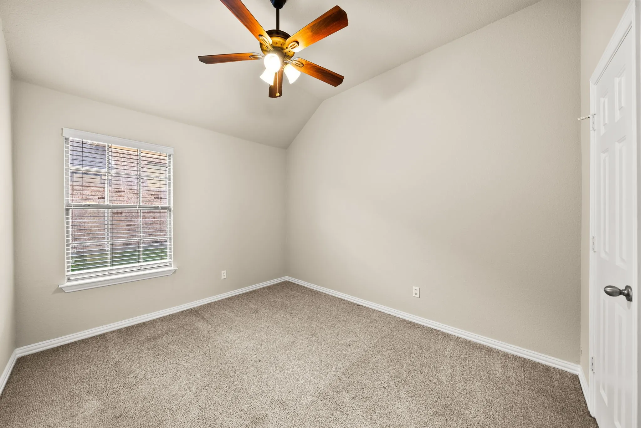 Vaulted ceiling with an attached ceiling fan, neutral wall tones, and carpeted flooring