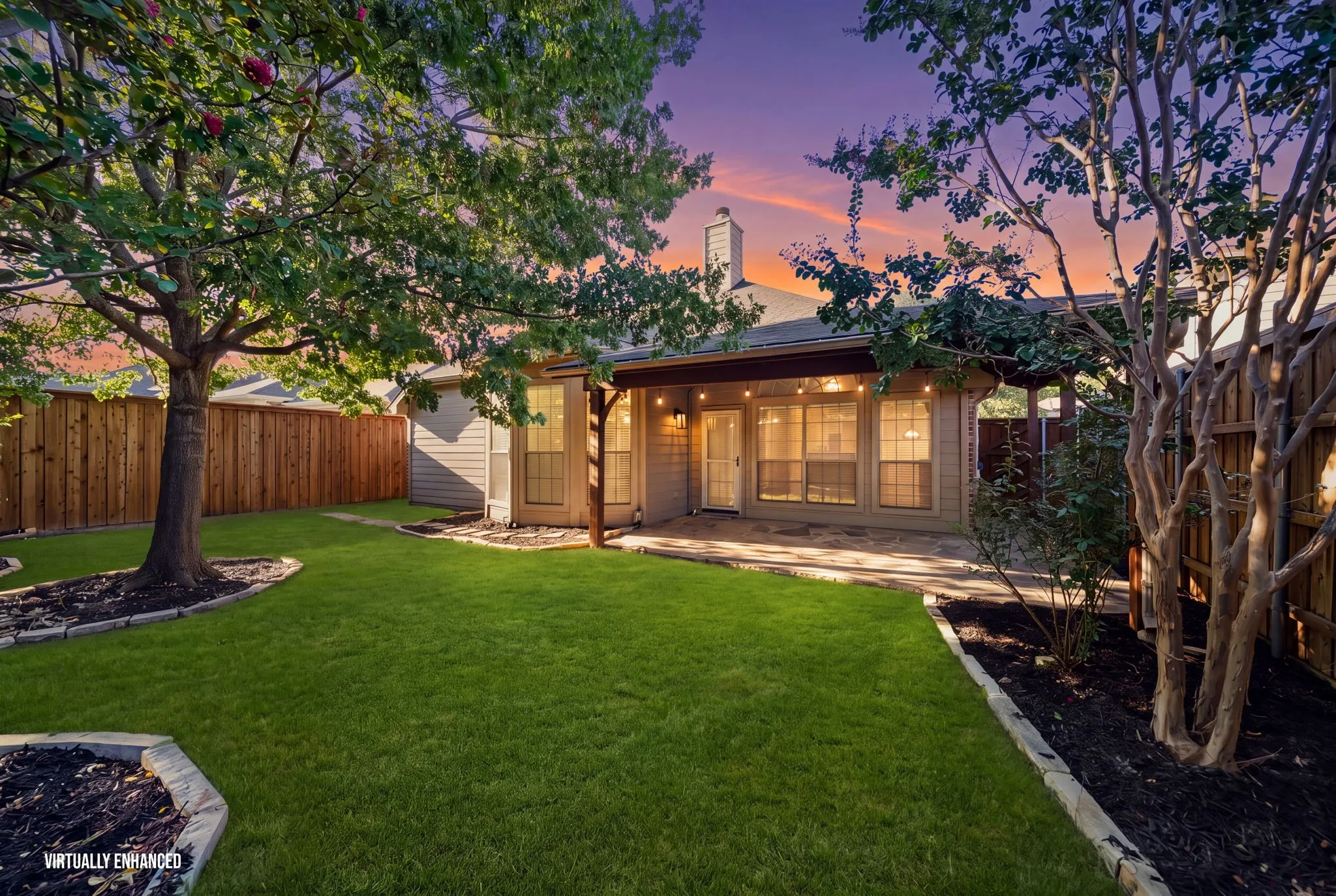 Expansive backyard featuring a manicured lawn, established trees, and a wooden privacy fence