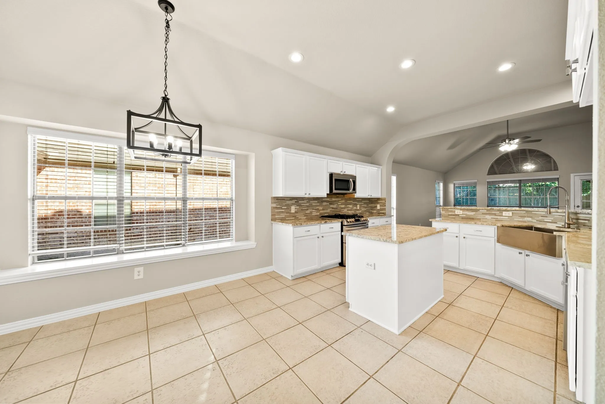 Kitchen featuring white cabinetry, a central island with a granite countertop, stainless steel appliances, a tile backsplash, and recessed lighting