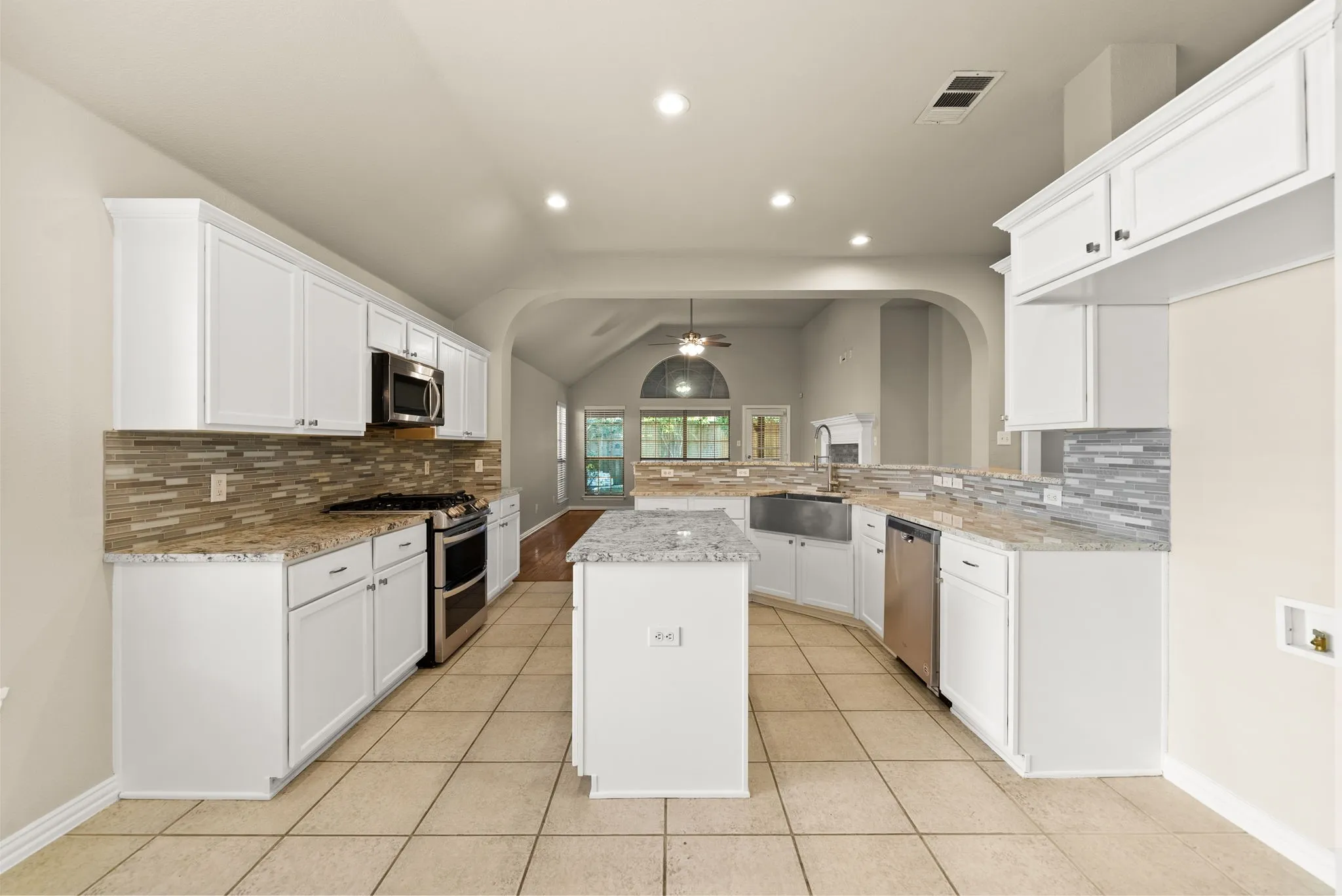 Kitchen featuring white cabinetry, stainless steel appliances, granite countertops, and a tile backsplash