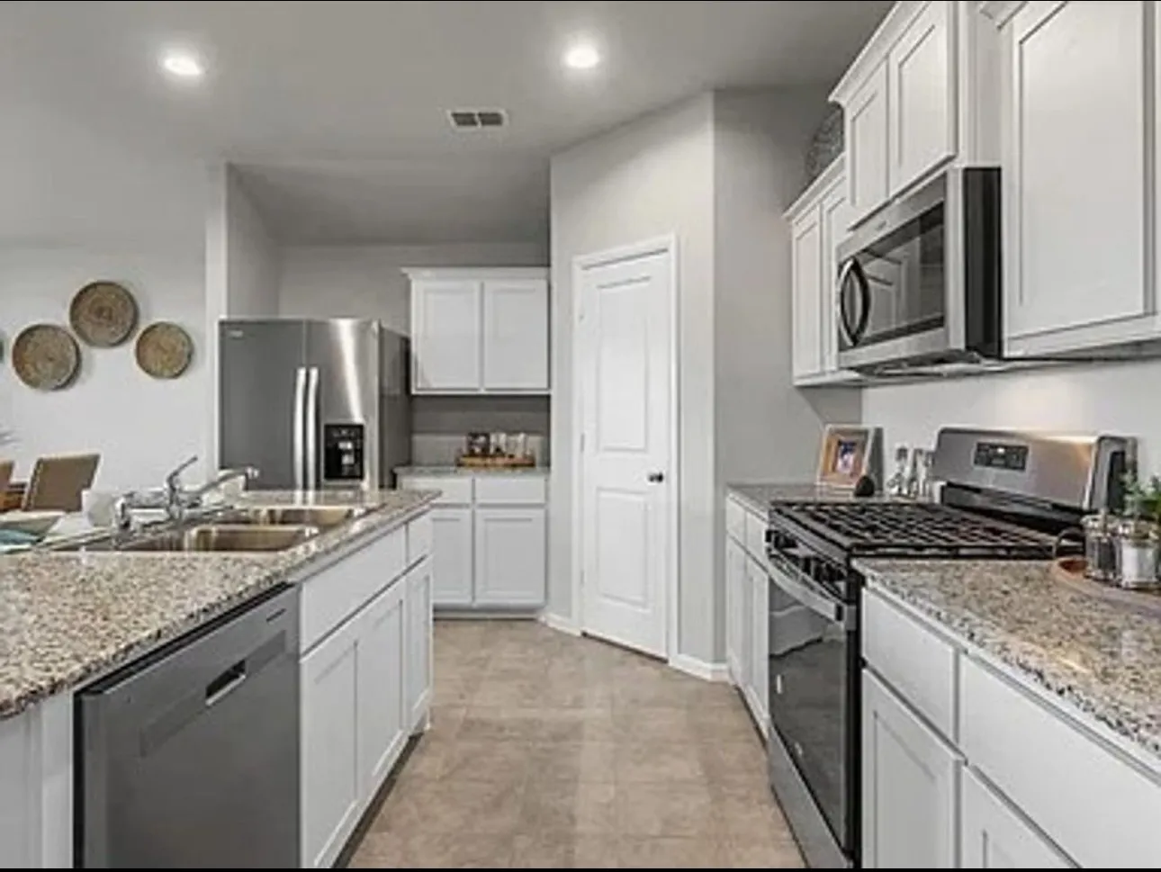 Kitchen with stainless steel appliances, recessed lighting, light stone countertops, and white cabinetry
