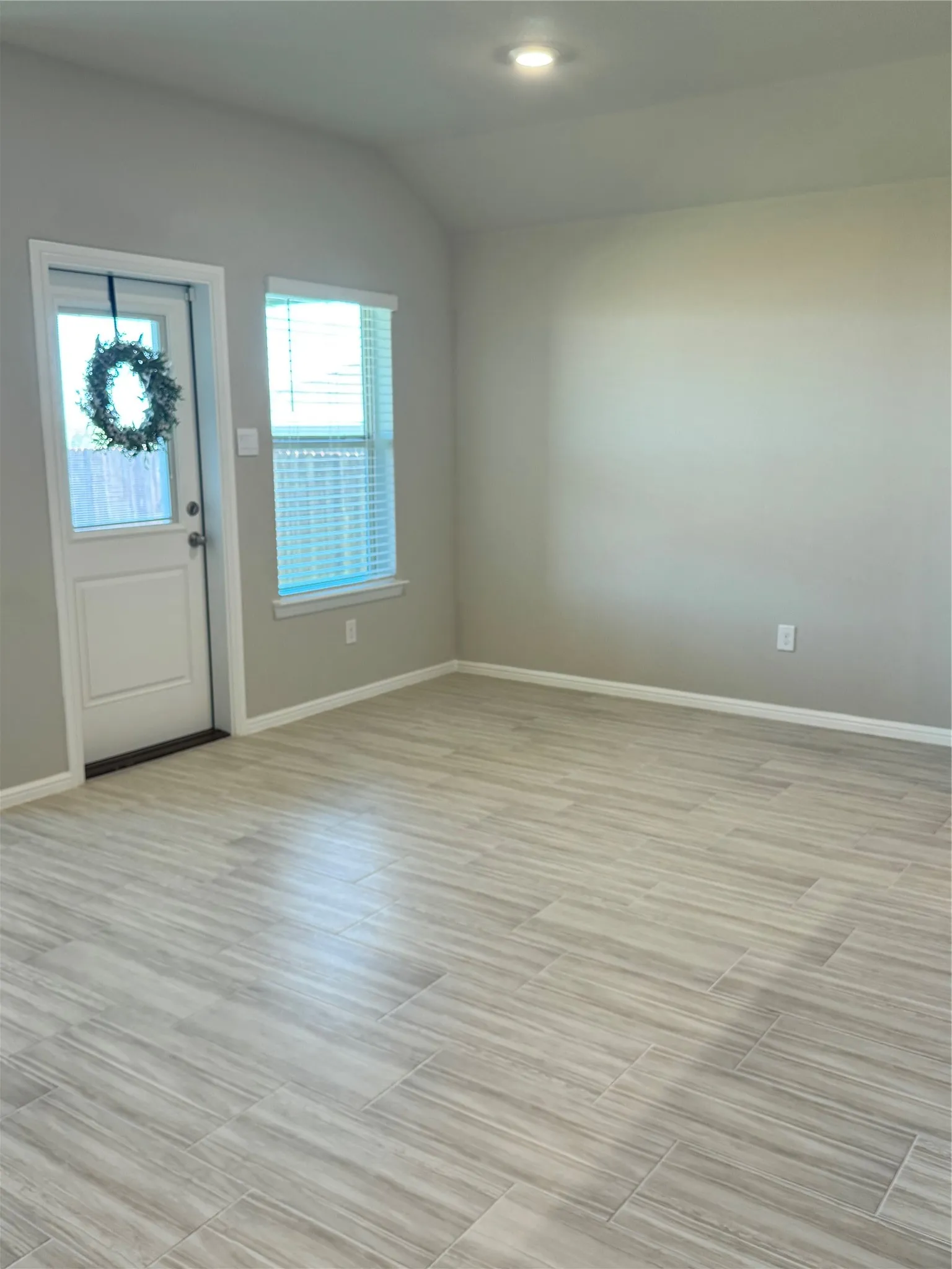 Foyer featuring vaulted ceiling and wood tiled floors