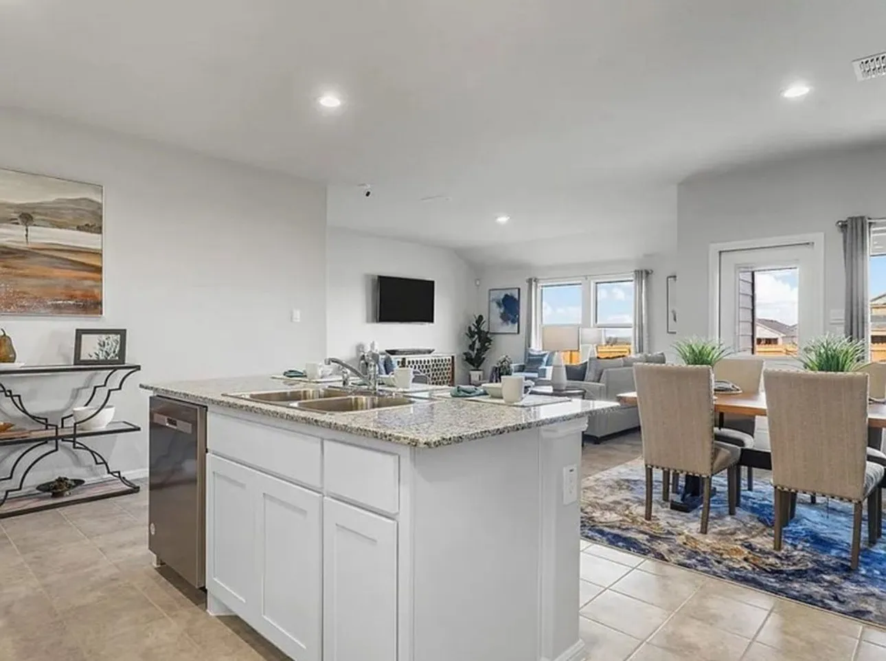 Kitchen featuring white cabinets, light stone countertops, a center island with sink, dishwasher, and recessed lighting