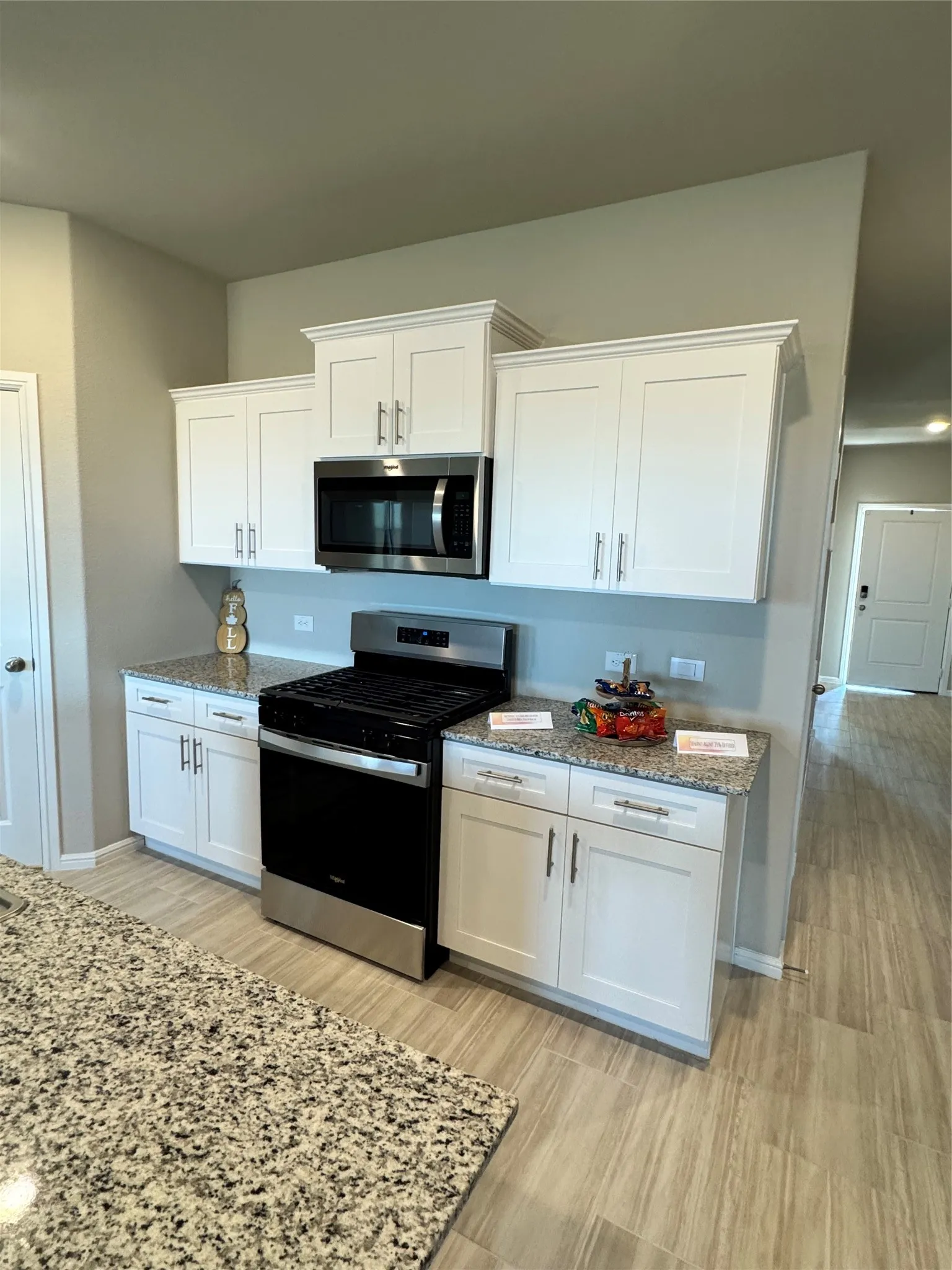 Kitchen featuring stainless steel range, white cabinetry, light stone counters, and light wood-style flooring