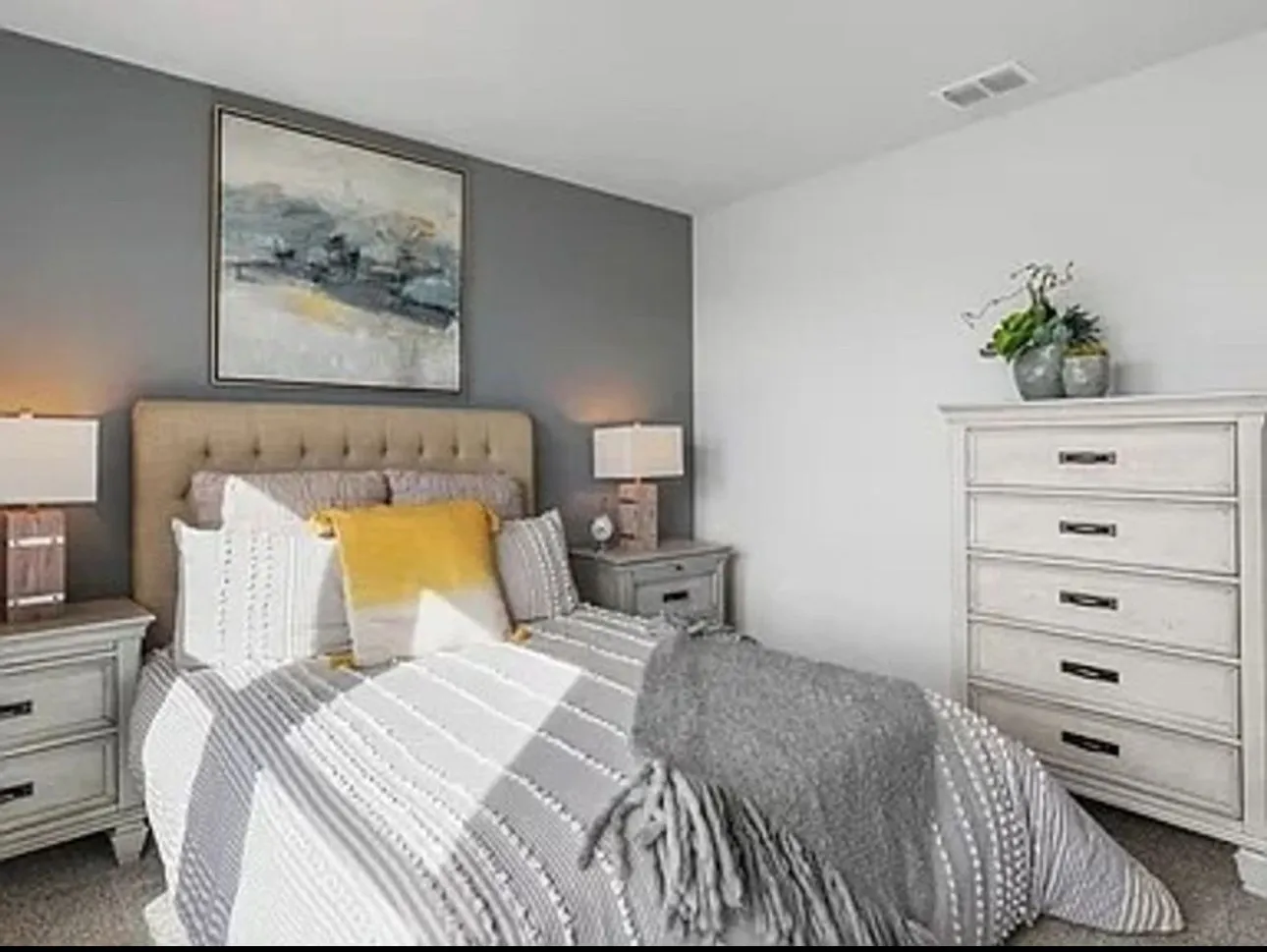Staged Bedroom with dark colored carpet.  Home is currently vacant and does not have an accent wall color.