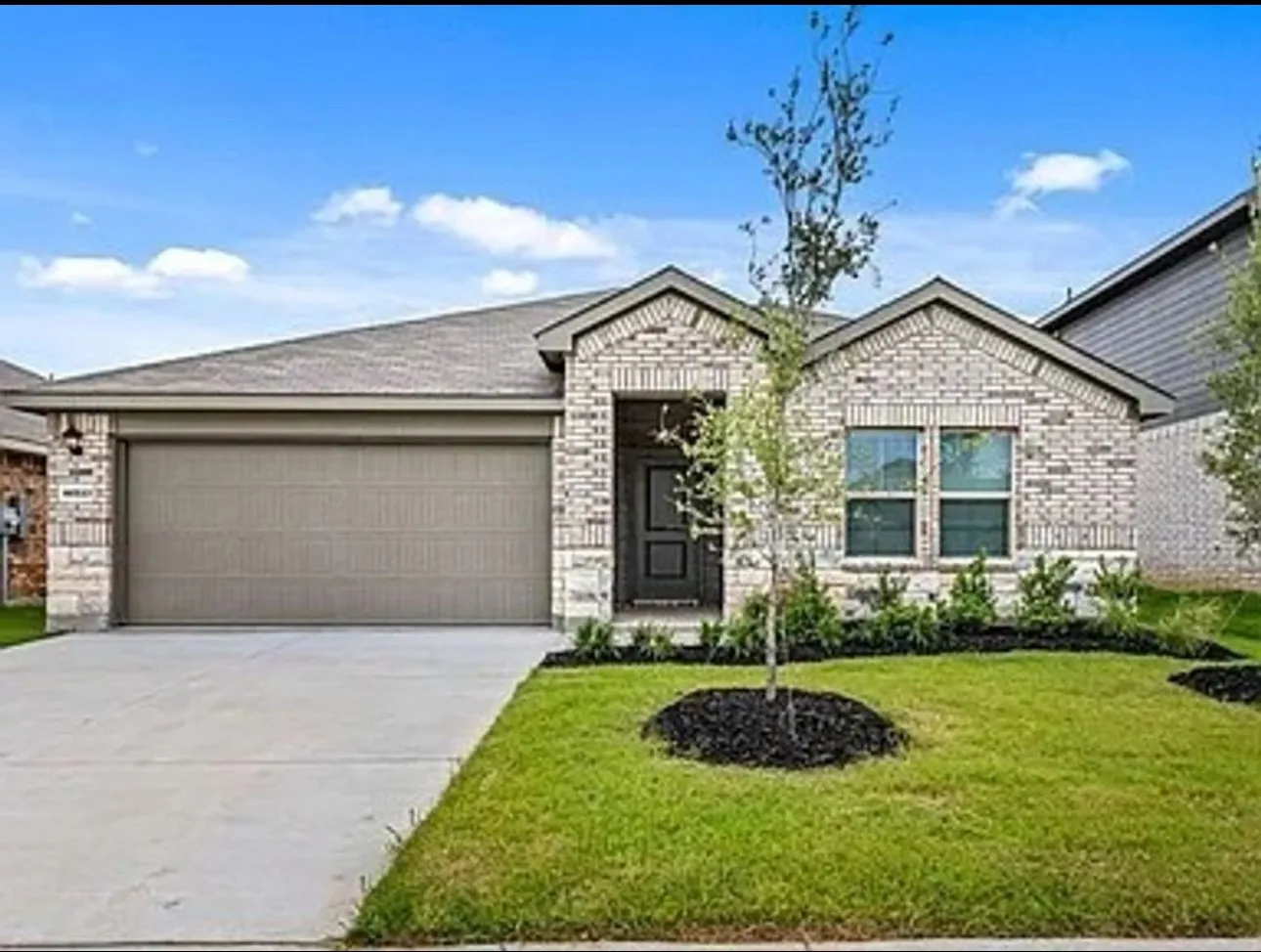 Single story home with concrete driveway, a front yard, brick siding, and an attached garage
