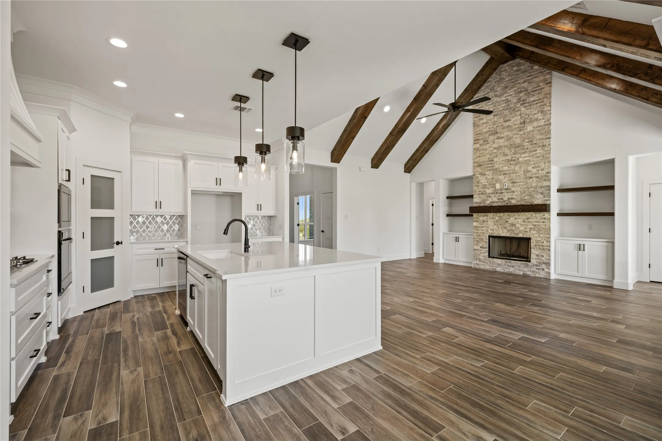 Gourmet kitchen with white cabinetry and quartz countertops, featuring a large center island and modern pendant lighting