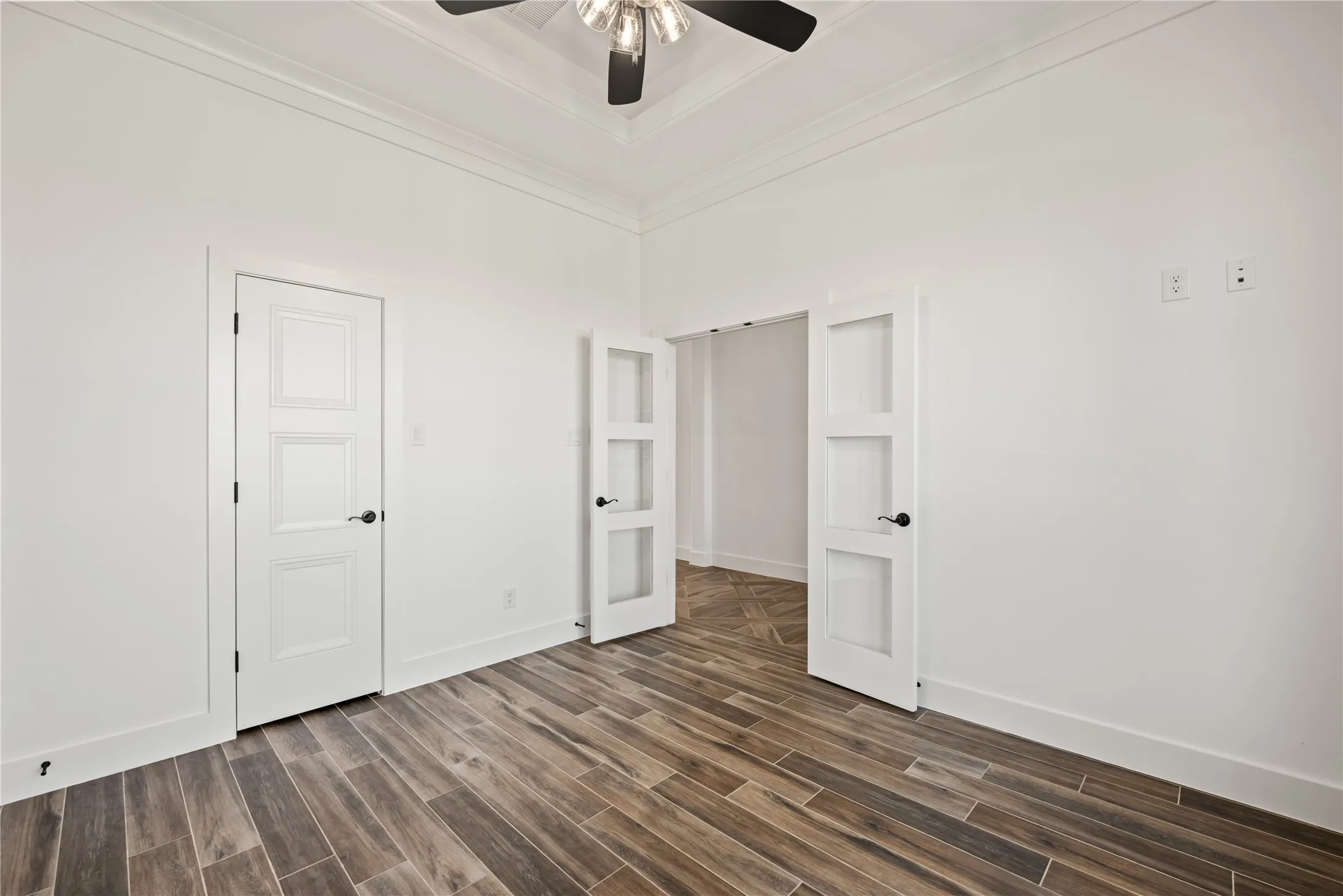 Wood-finish tile flooring throughout, crown molding, white walls, and a recessed ceiling