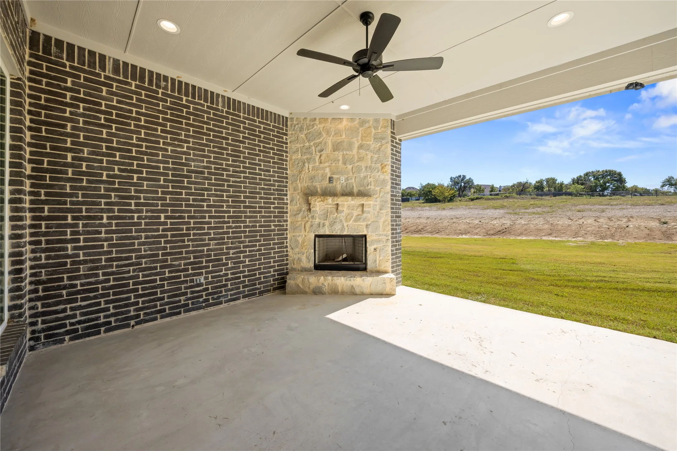Covered outdoor patio with a stone-clad fireplace and hearth