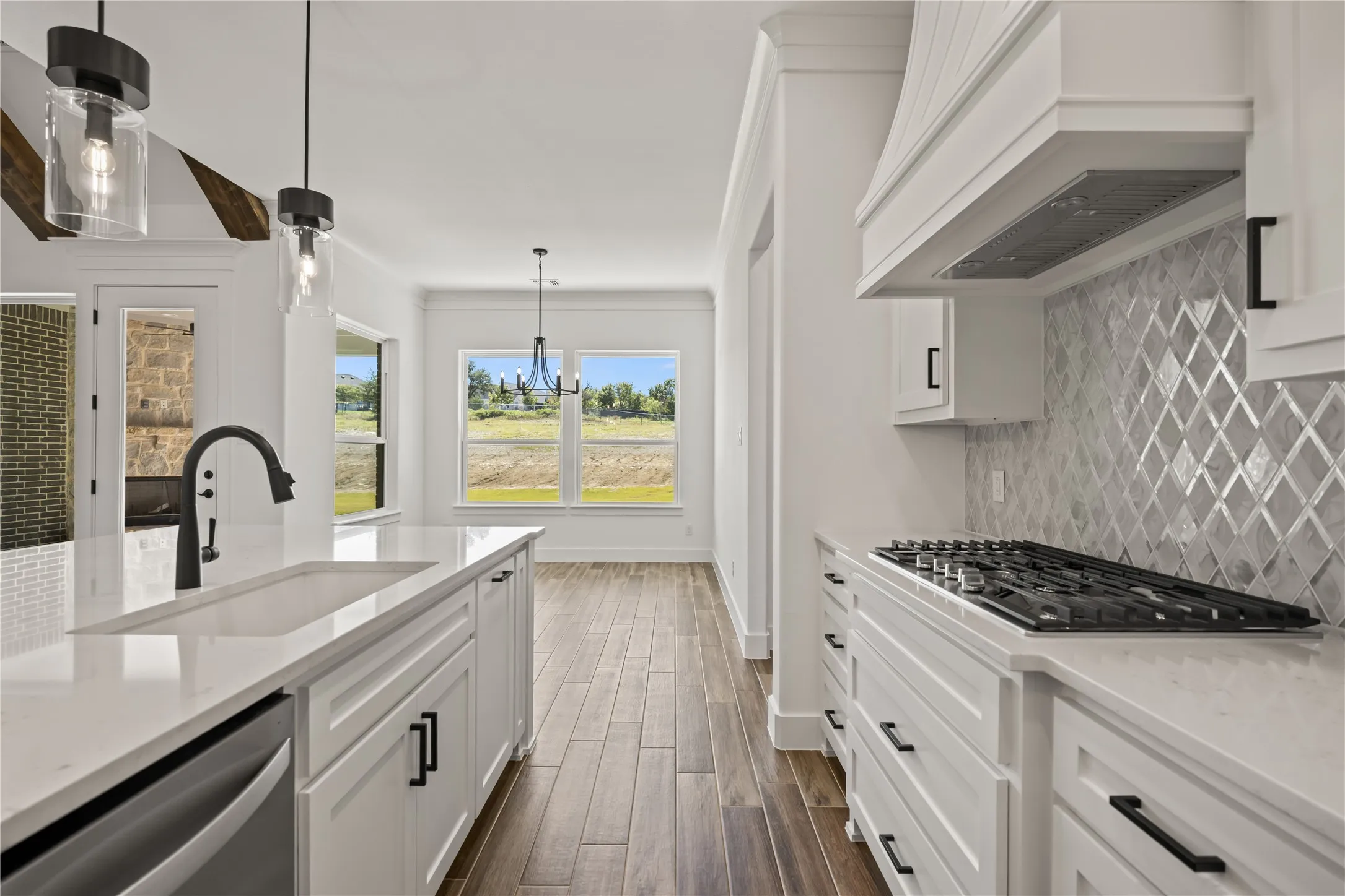 White cabinetry with black hardware, wood-finish flooring, white countertops, glass subway tile backsplash, and a built-in gas range