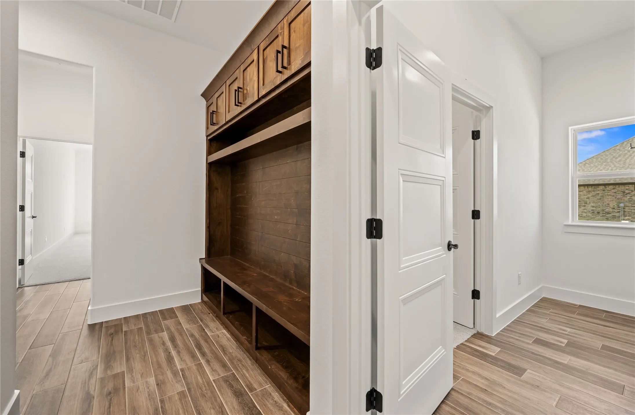 Built-in wood-finish storage bench with upper cabinetry
