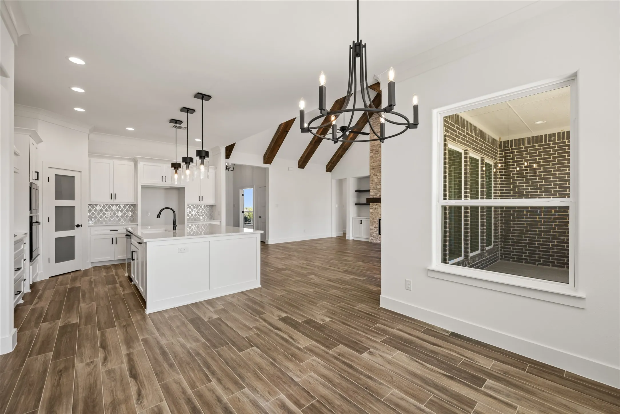 Open-concept living space with wood-finish flooring, white cabinetry, a kitchen island, and a decorative chandelier