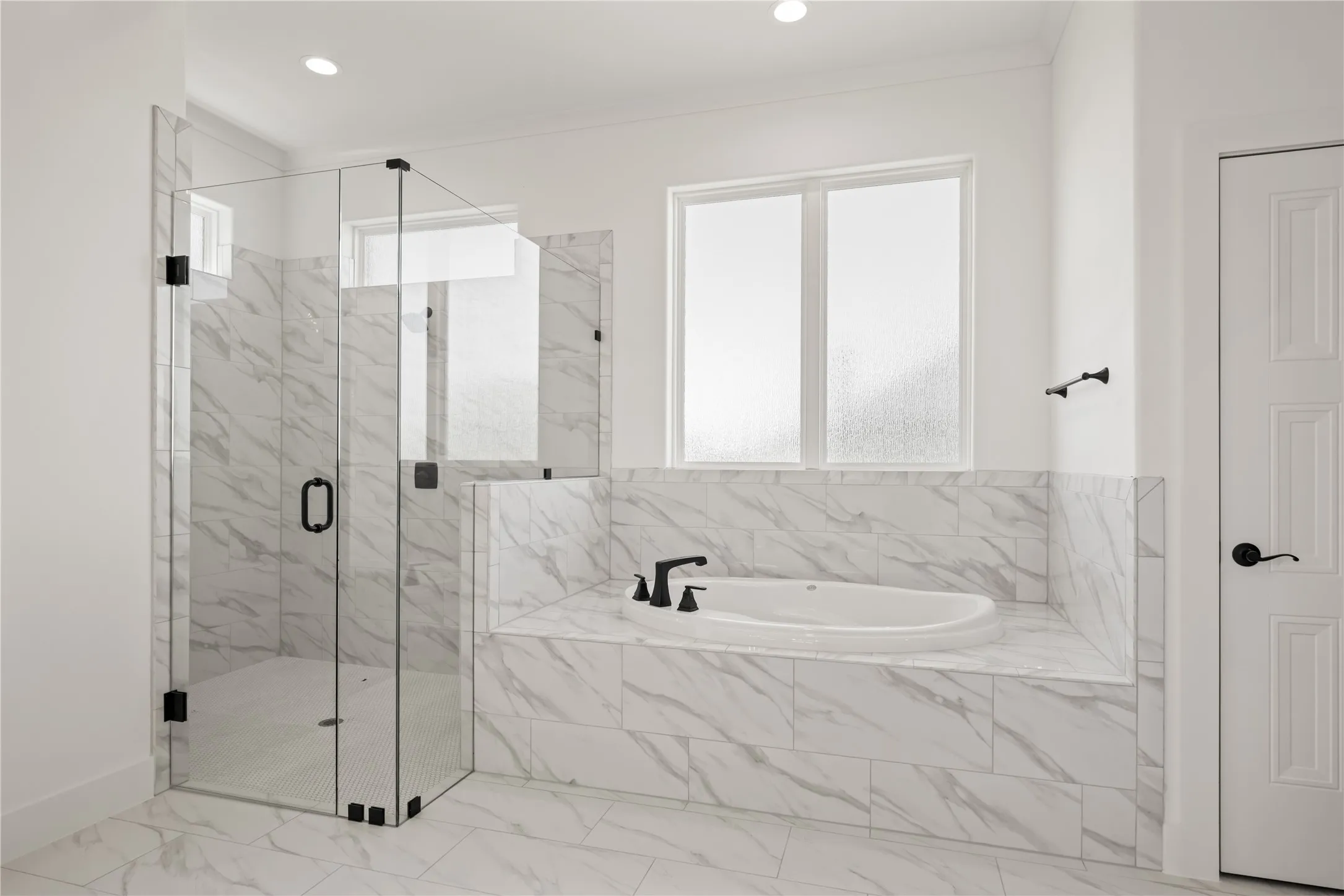 Walk-in shower with clear glass enclosure, built-in soaking tub, tile surround, and matte black fixtures