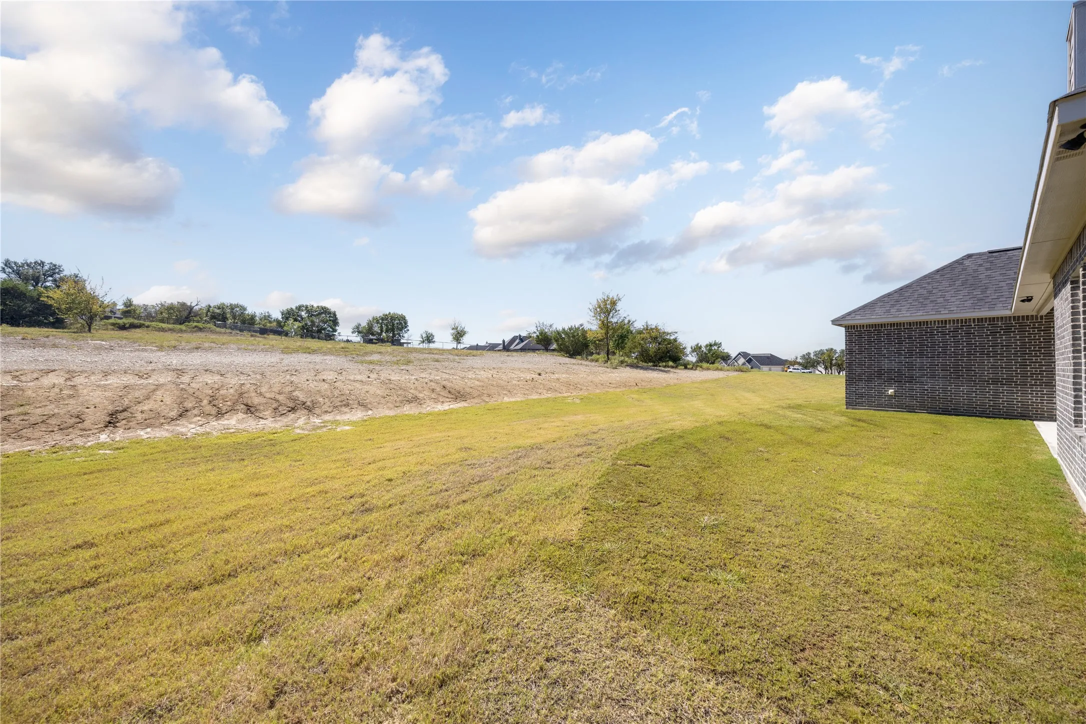 Expansive grassy area with a partial brick exterior