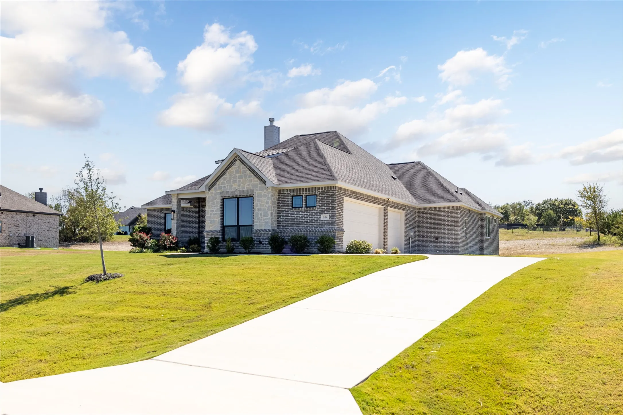 Contemporary single-story residence with a stone and brick facade, a two-car garage, and a concrete driveway