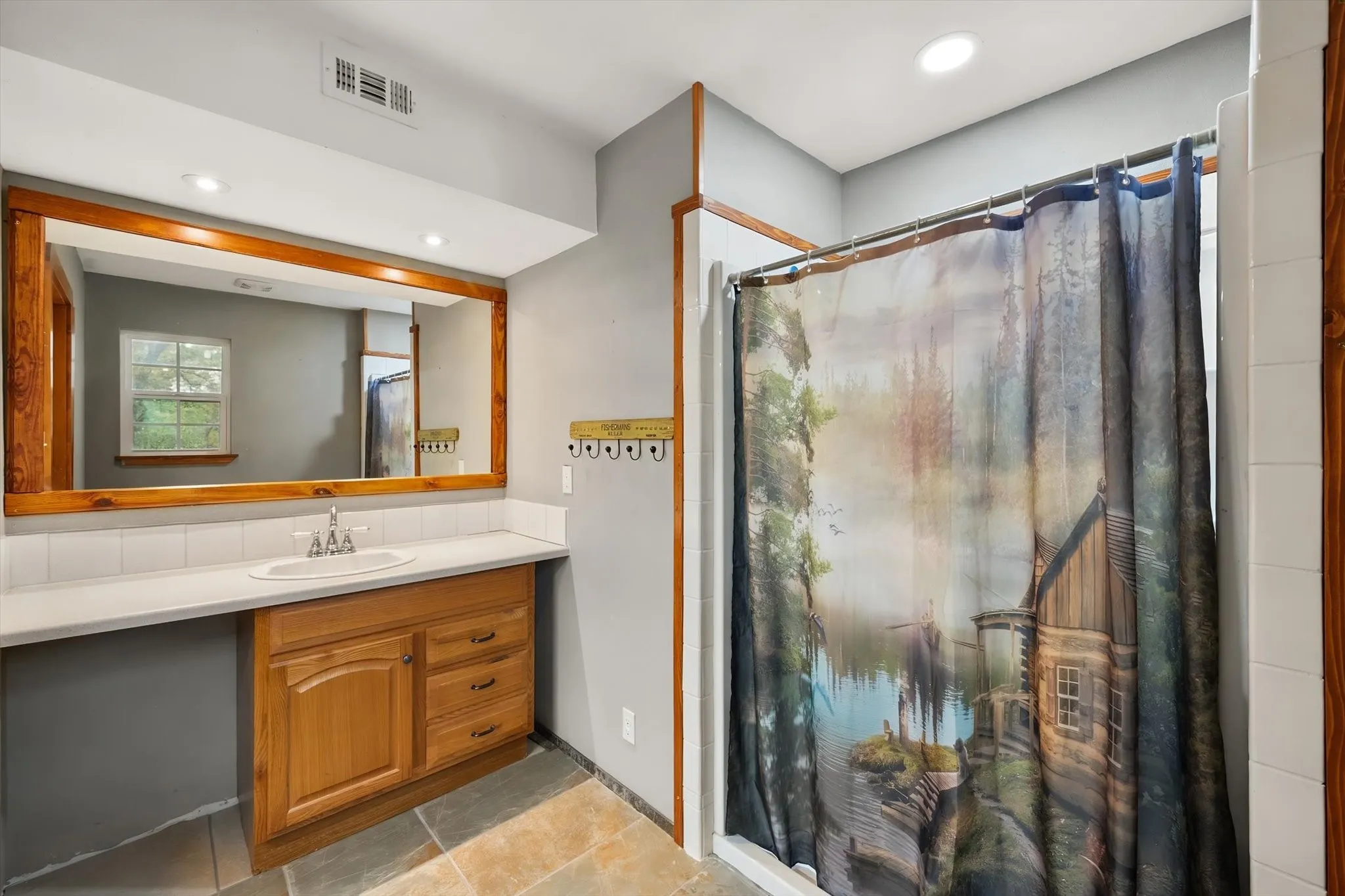 Vanity with wood-finish cabinetry, a white countertop, and a large wood-framed mirror