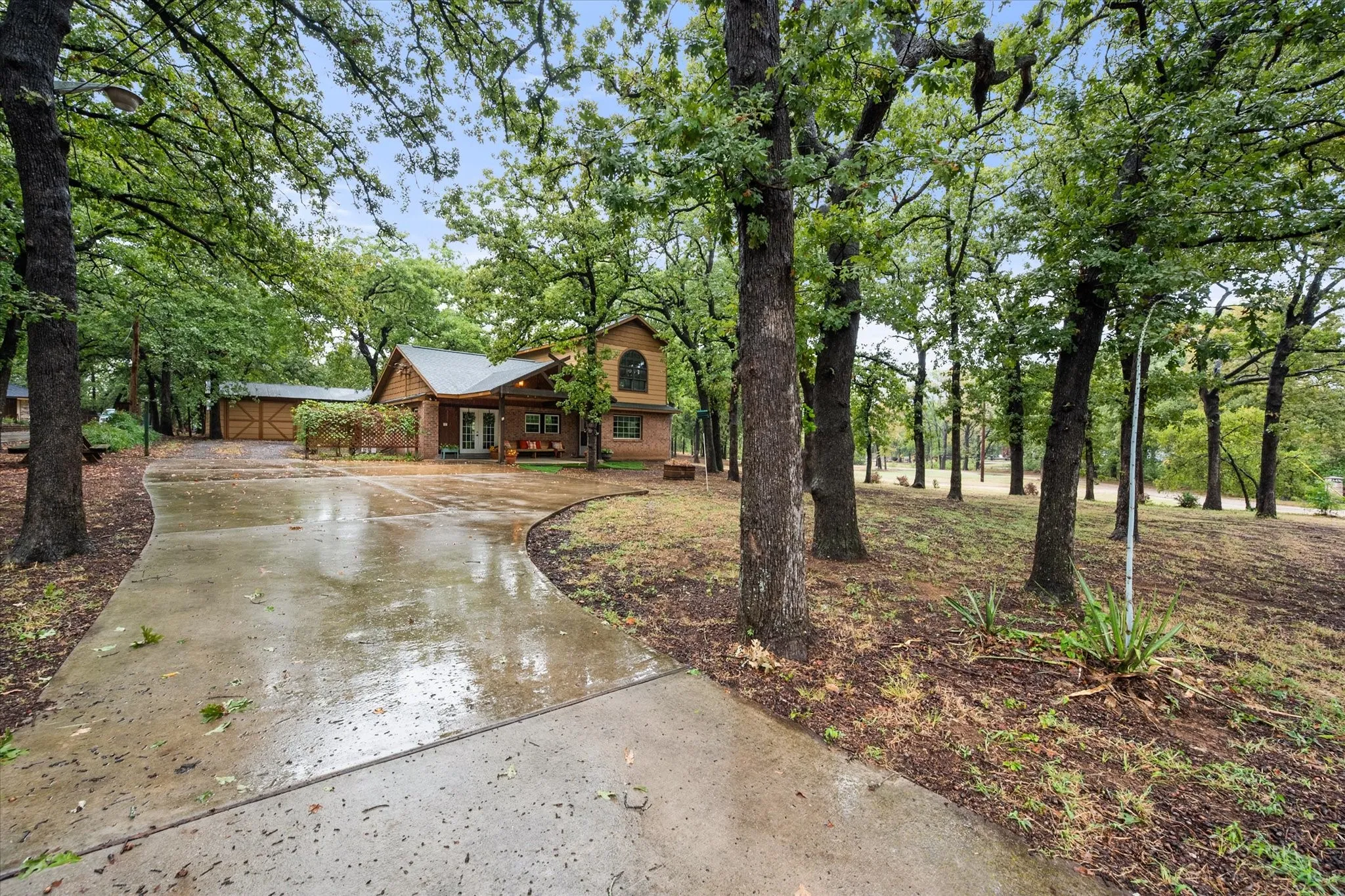 Concrete driveway leading to a multi-level home featuring brick and wood siding