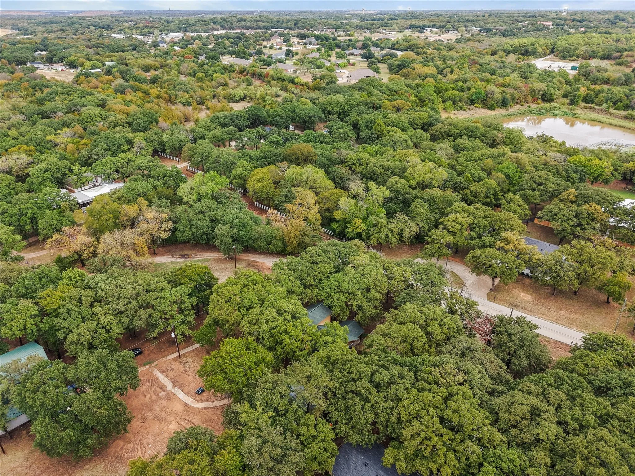 Expansive treed landscape with a visible pond and paved roadways