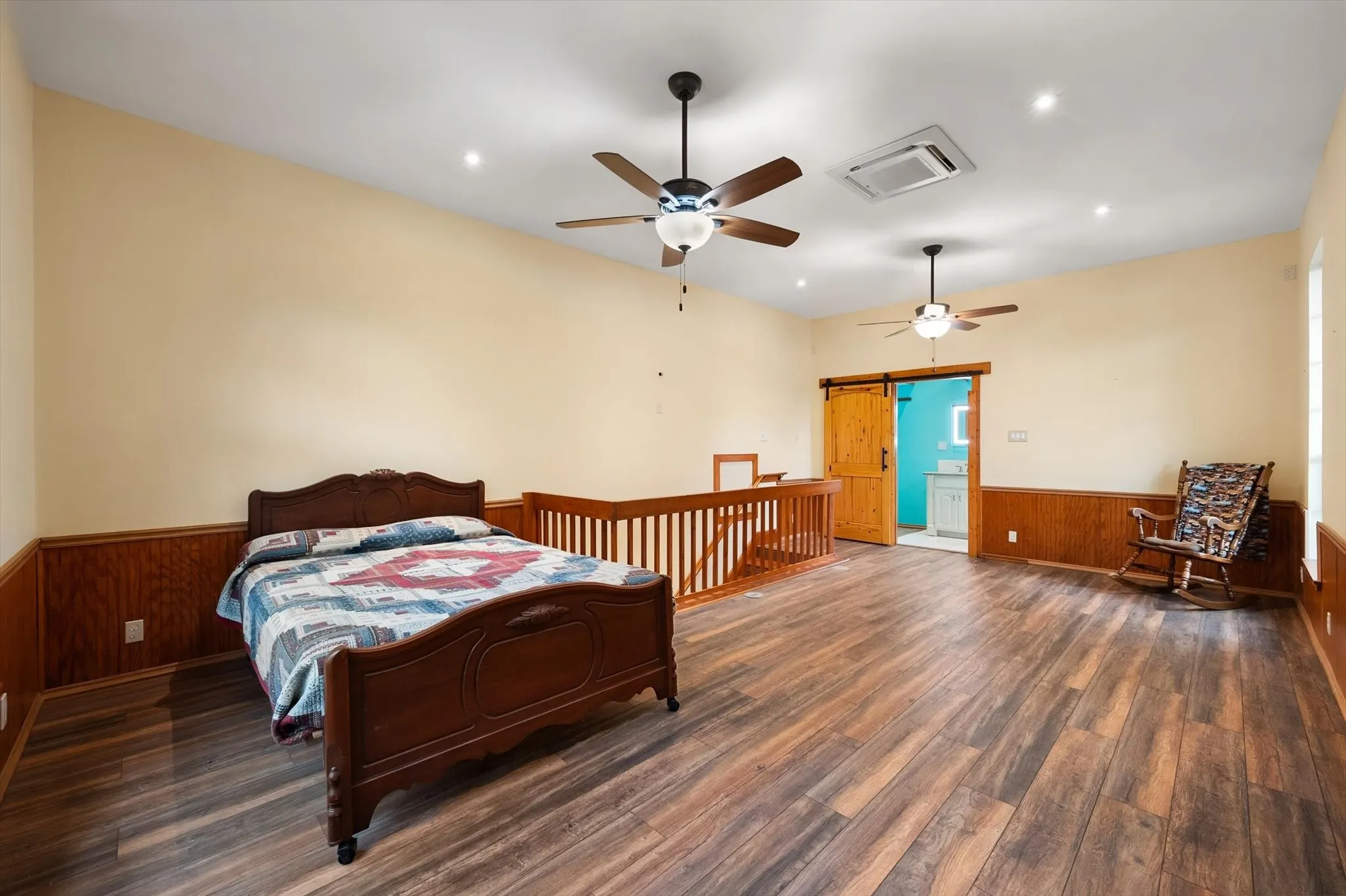 Expansive room featuring wood-finish flooring, two ceiling fans, recessed lighting, and wood paneling