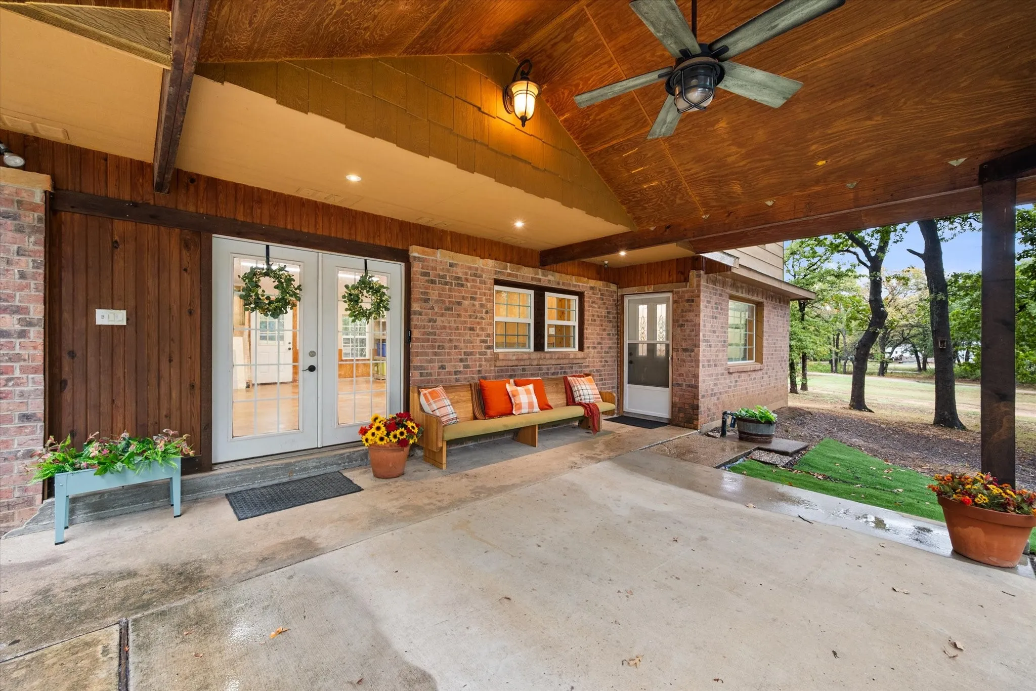 Expansive covered patio with a wood-plank ceiling, exposed beams, and a ceiling fan
