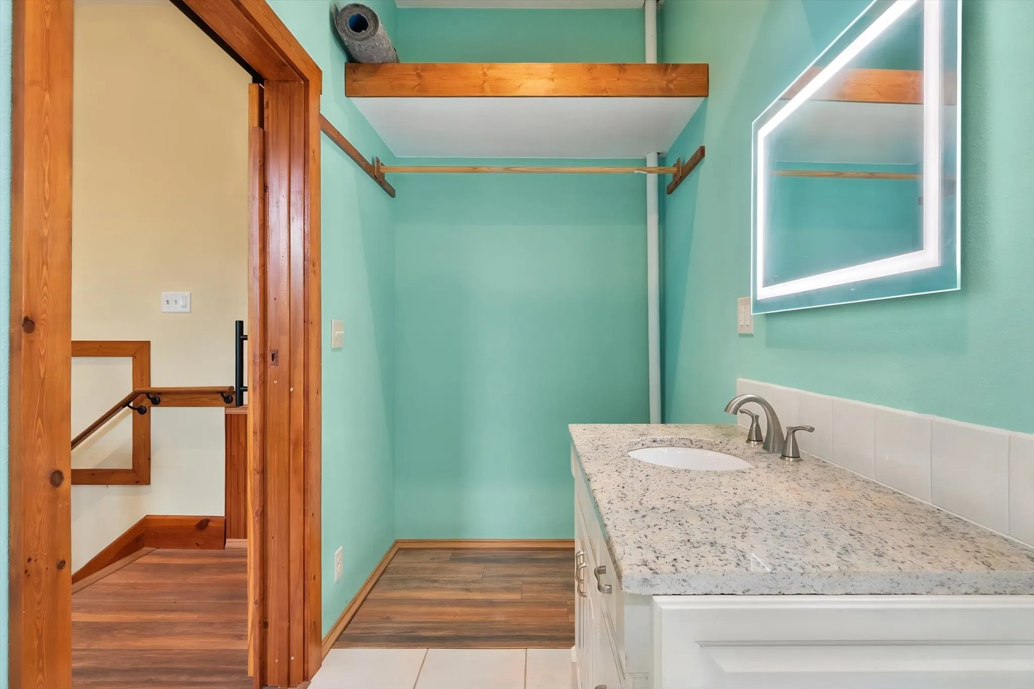 Built-in vanity with a granite countertop, undermount sink, and brushed nickel faucet