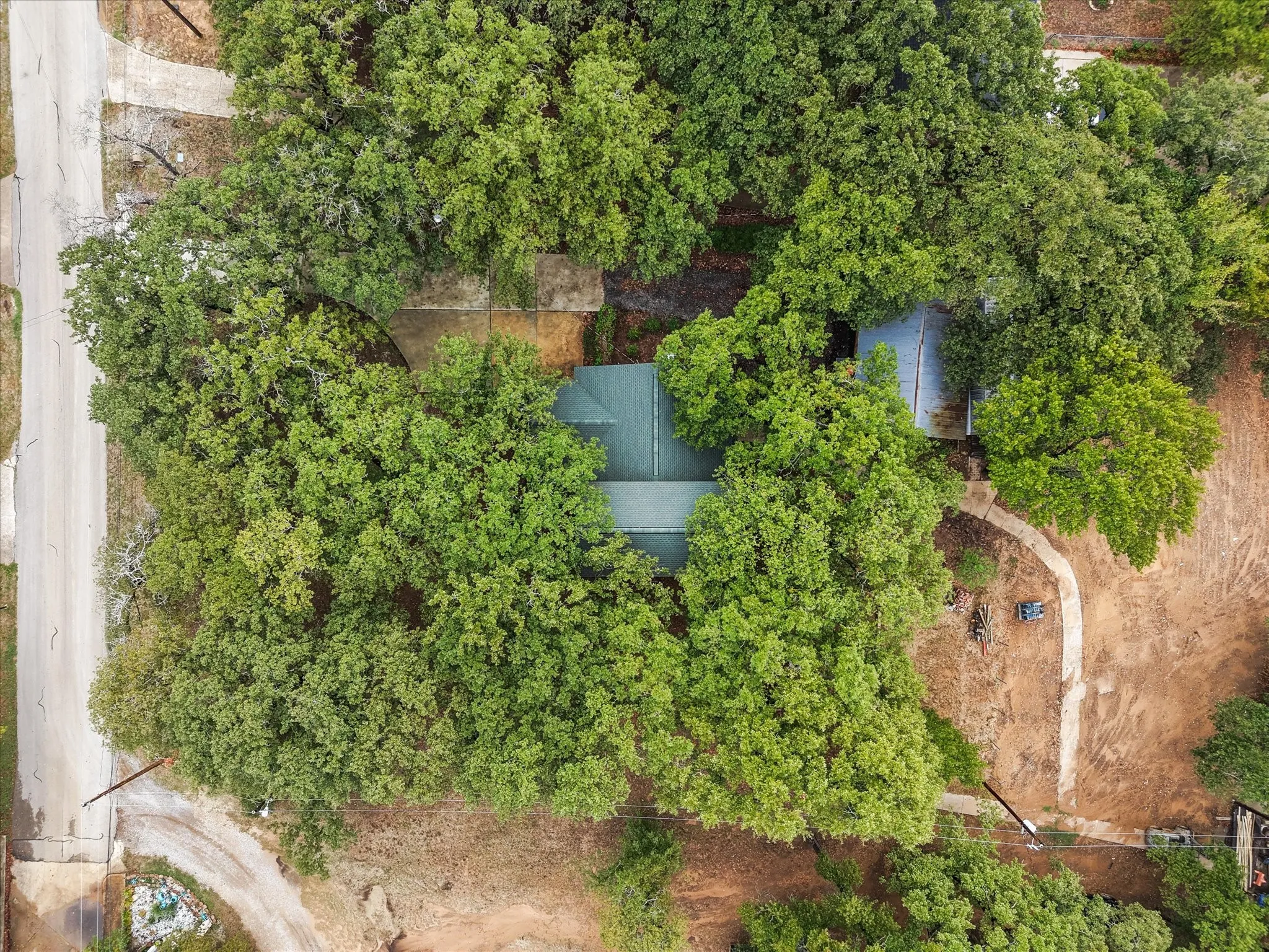 Property surrounded by mature trees, featuring a green shingle roof