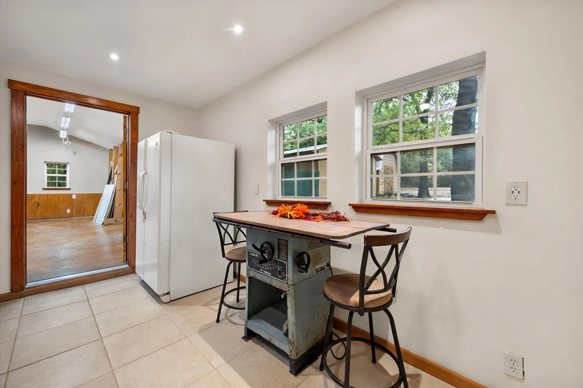 Neutral-toned tile flooring, recessed ceiling lighting, a wood-trimmed doorway, and double-hung windows with wood sills
