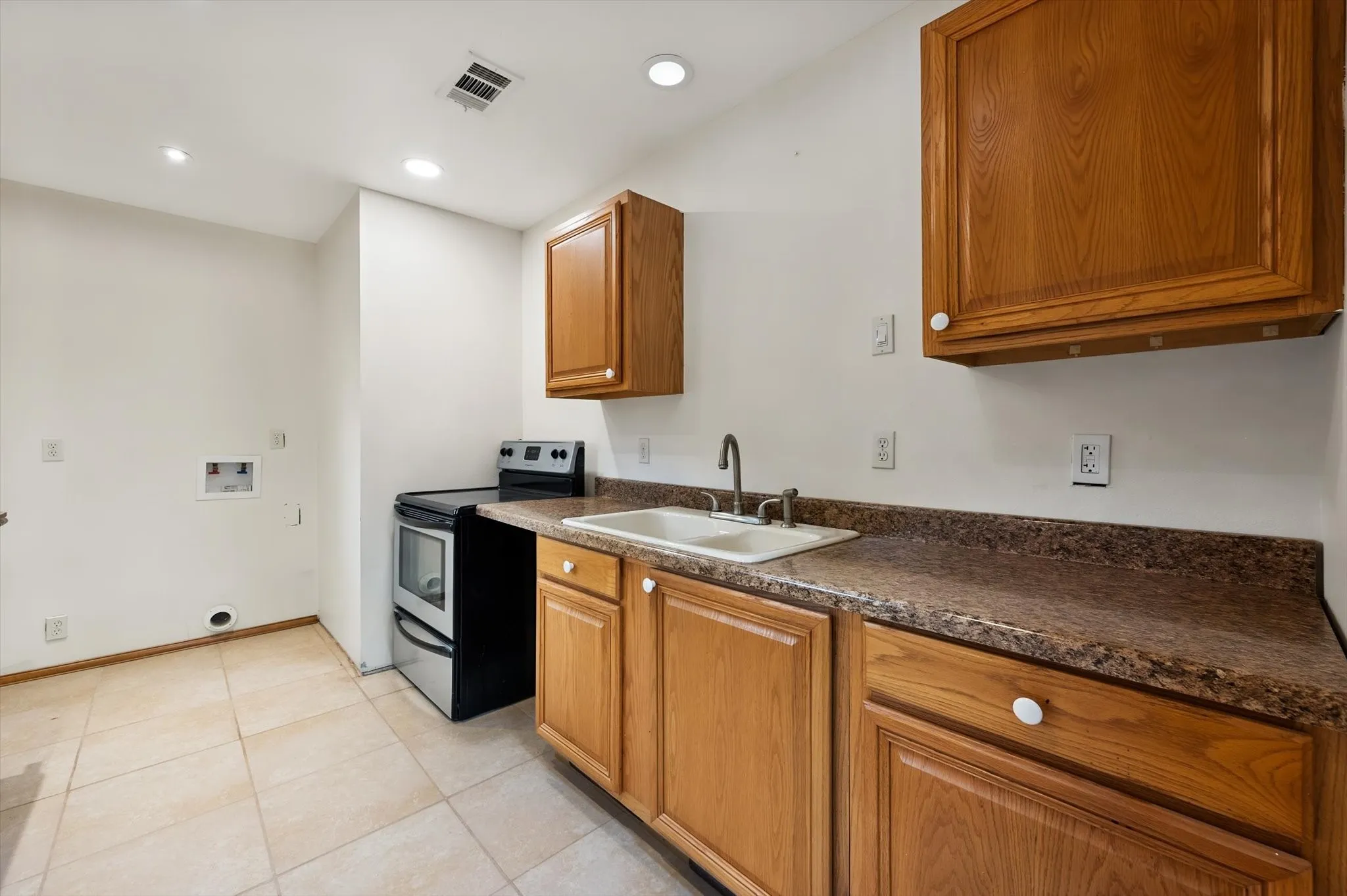 Tile flooring with integrated lighting, wood cabinetry, built-in sink, and a standalone range