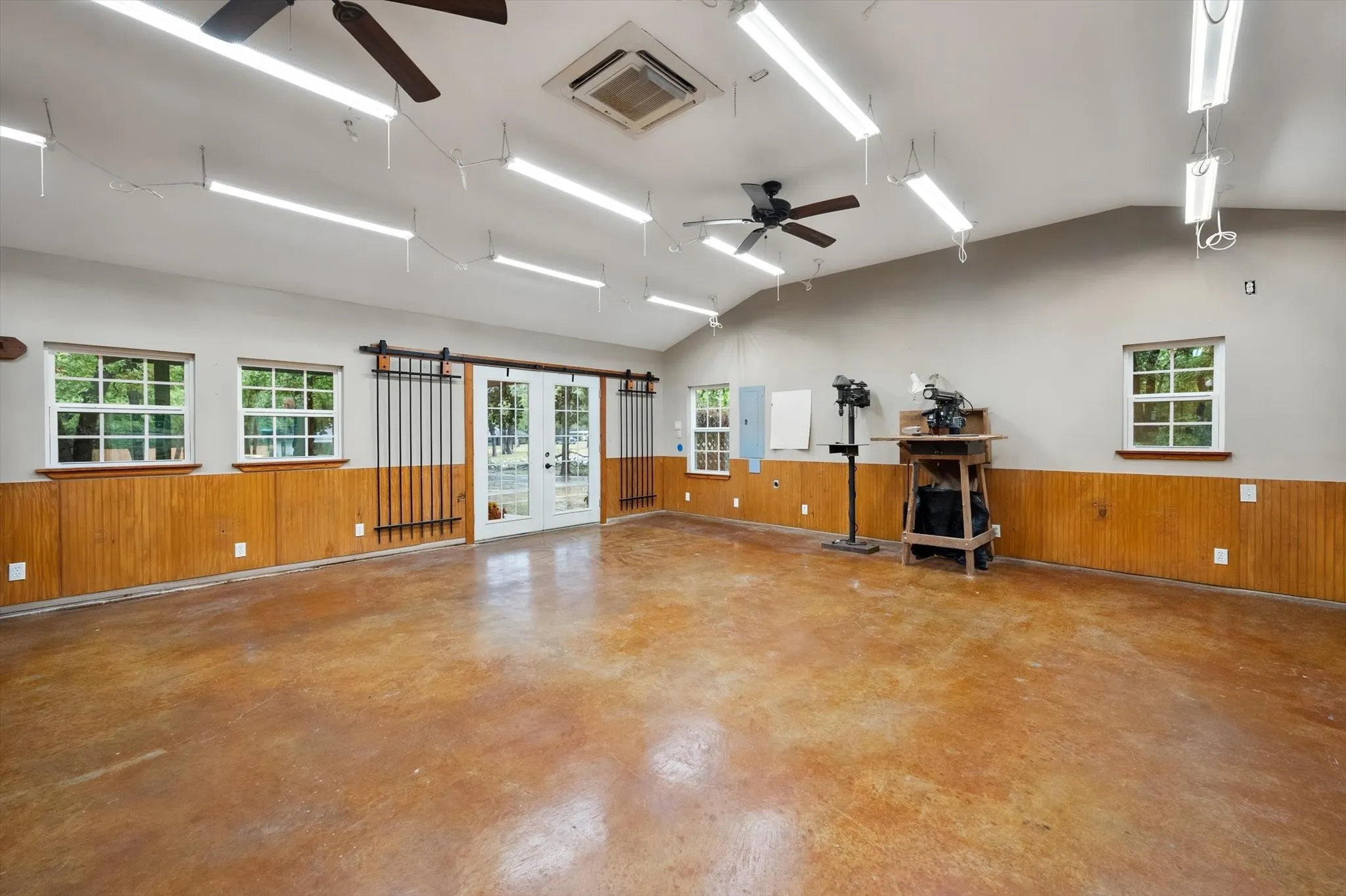 Spacious interior featuring a concrete floor, wood panel wainscoting, and multiple windows