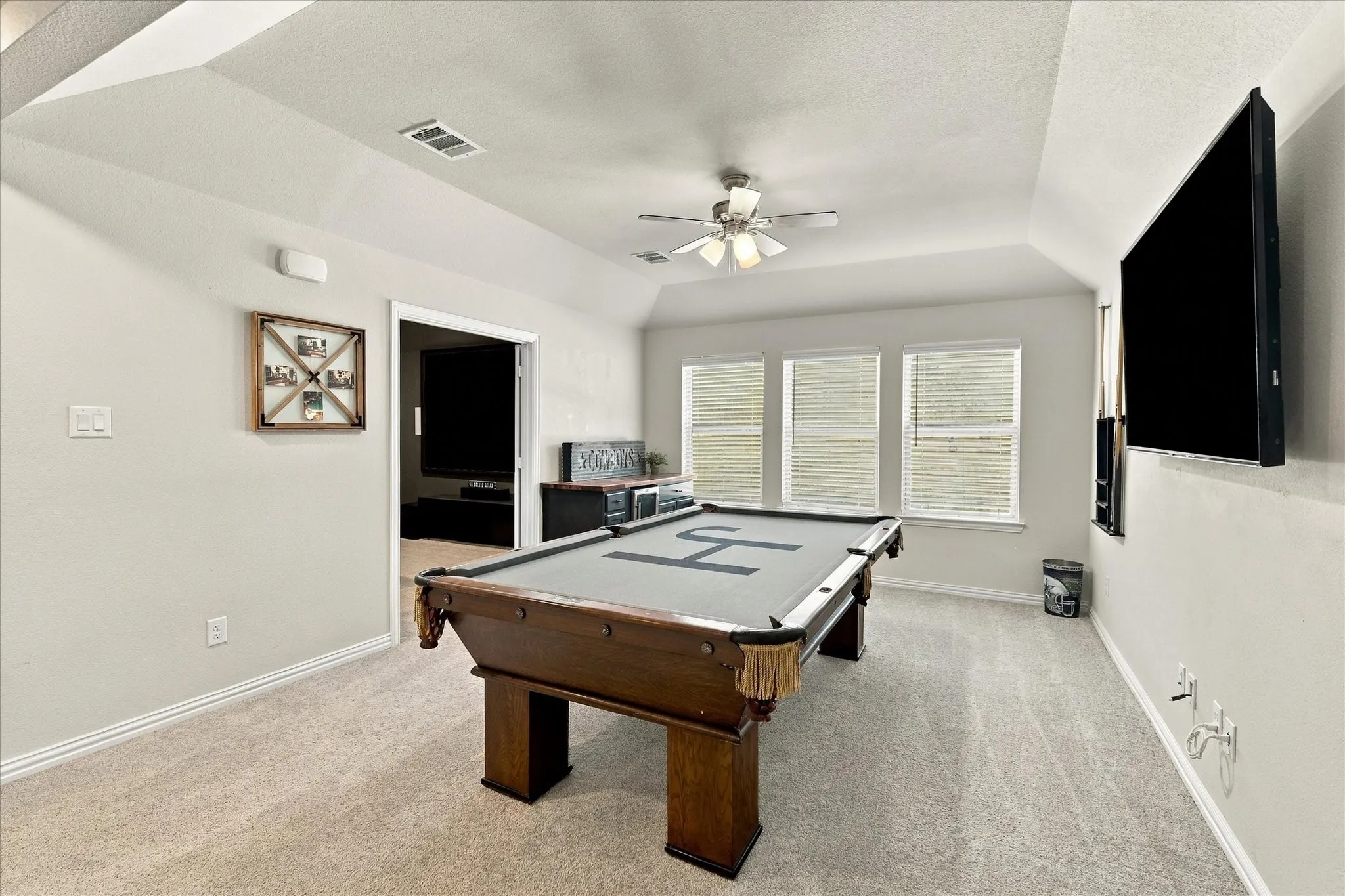 Sloped ceiling accentuating the room's height, plush carpet flooring, recessed lighting, and three panel windows with horizontal blinds