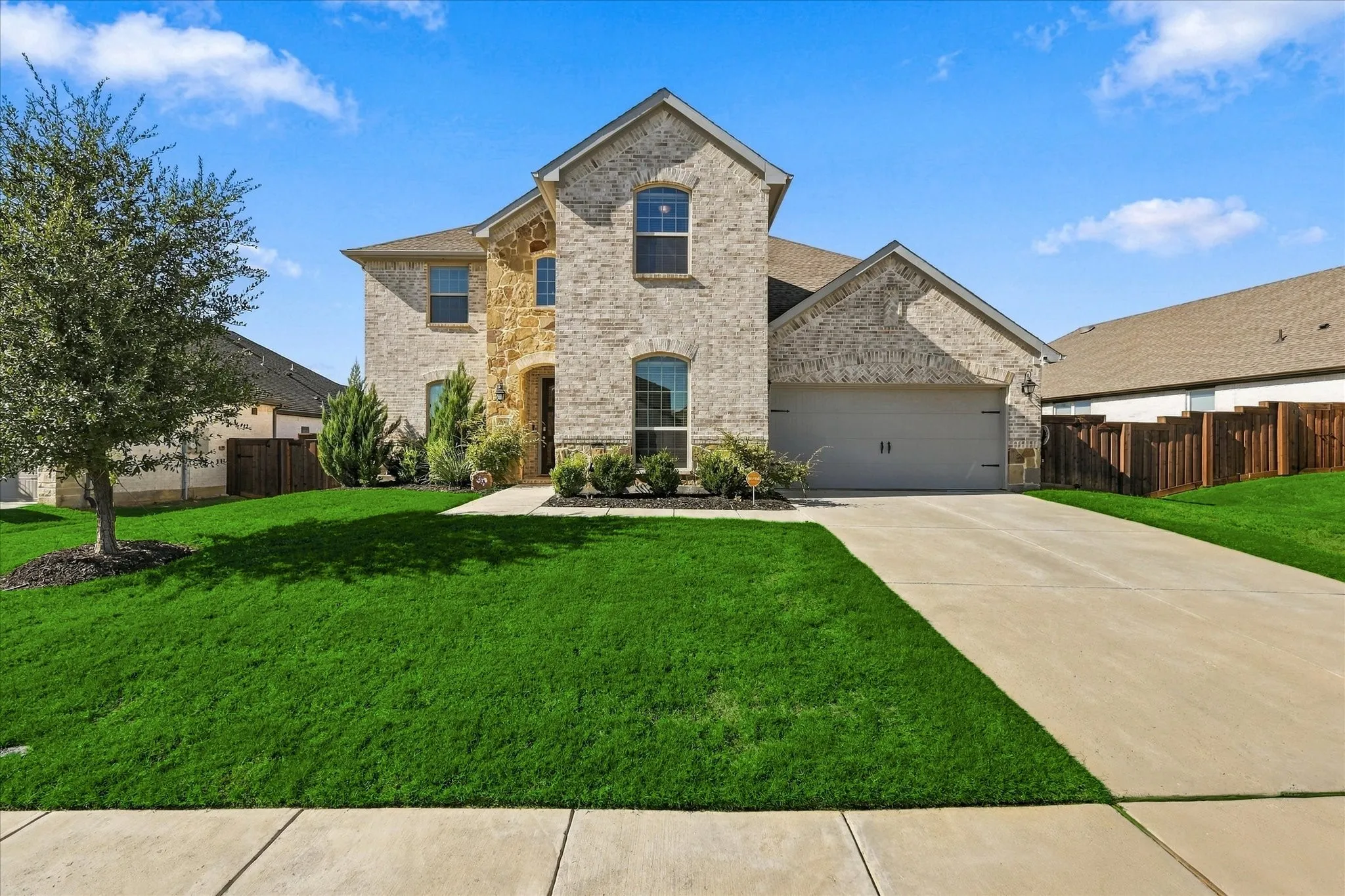 Two-story residence featuring a brick and stone facade, arched entry, and an attached two-car garage