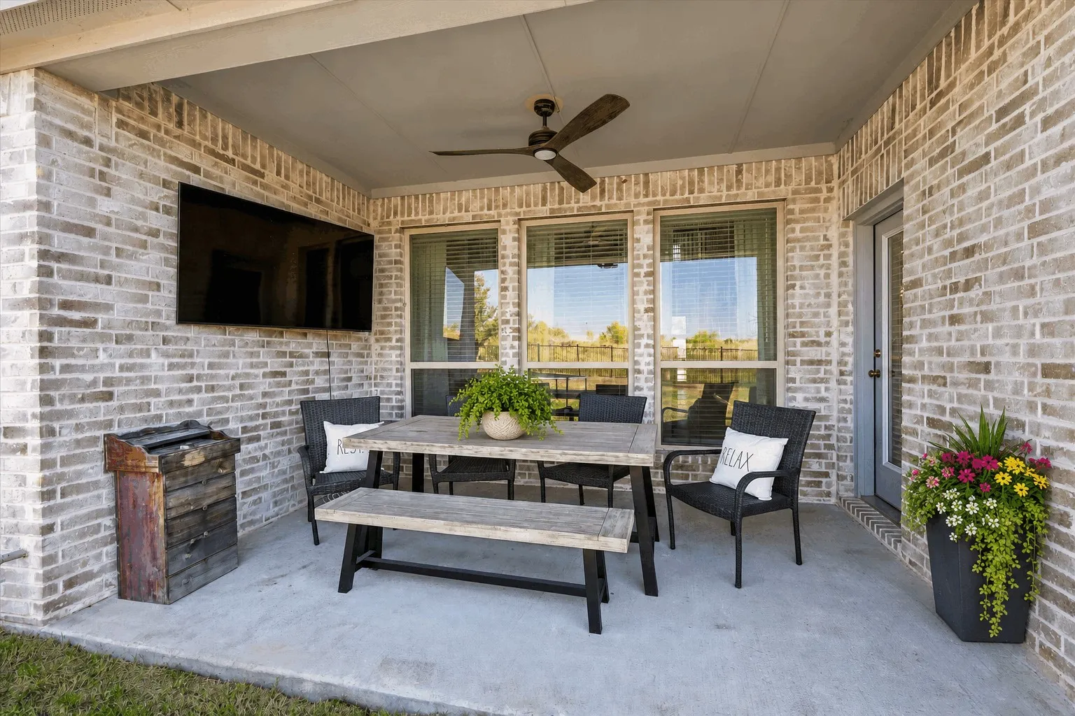 Covered patio featuring brick construction, concrete flooring, and a ceiling fan