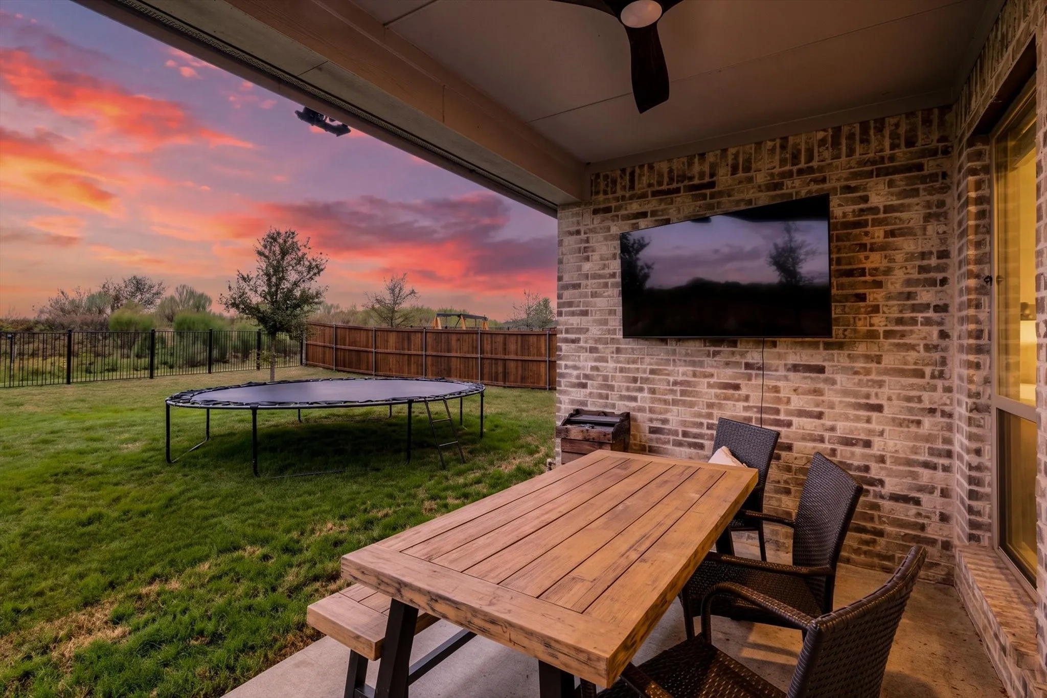 Covered patio featuring a ceiling fan, brick accent wall, and concrete flooring