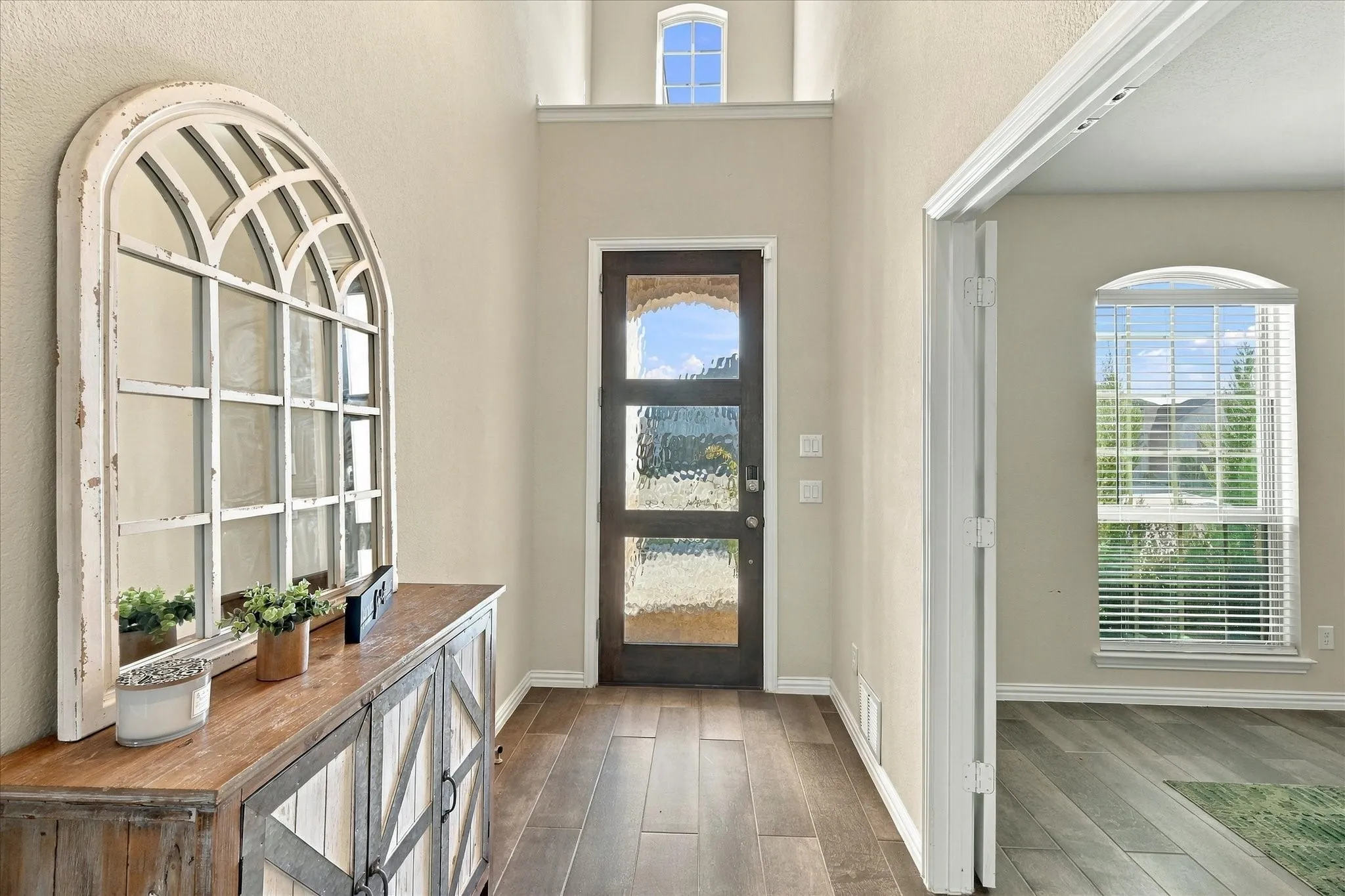 Wood-finish flooring throughout, frosted glass entry door, and an arched transom window