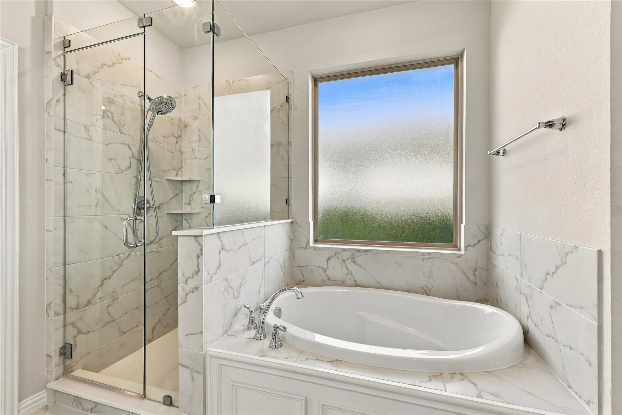 Built-in soaking tub with deck-mounted fixtures, frameless glass shower enclosure, and full-height wall tiling