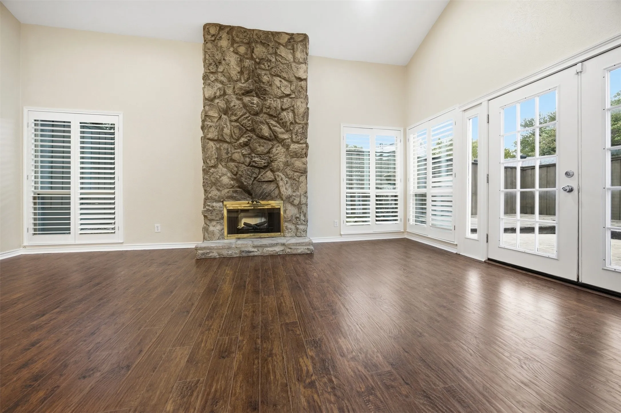 Vaulted ceiling with a stone-clad fireplace and brass-tone insert