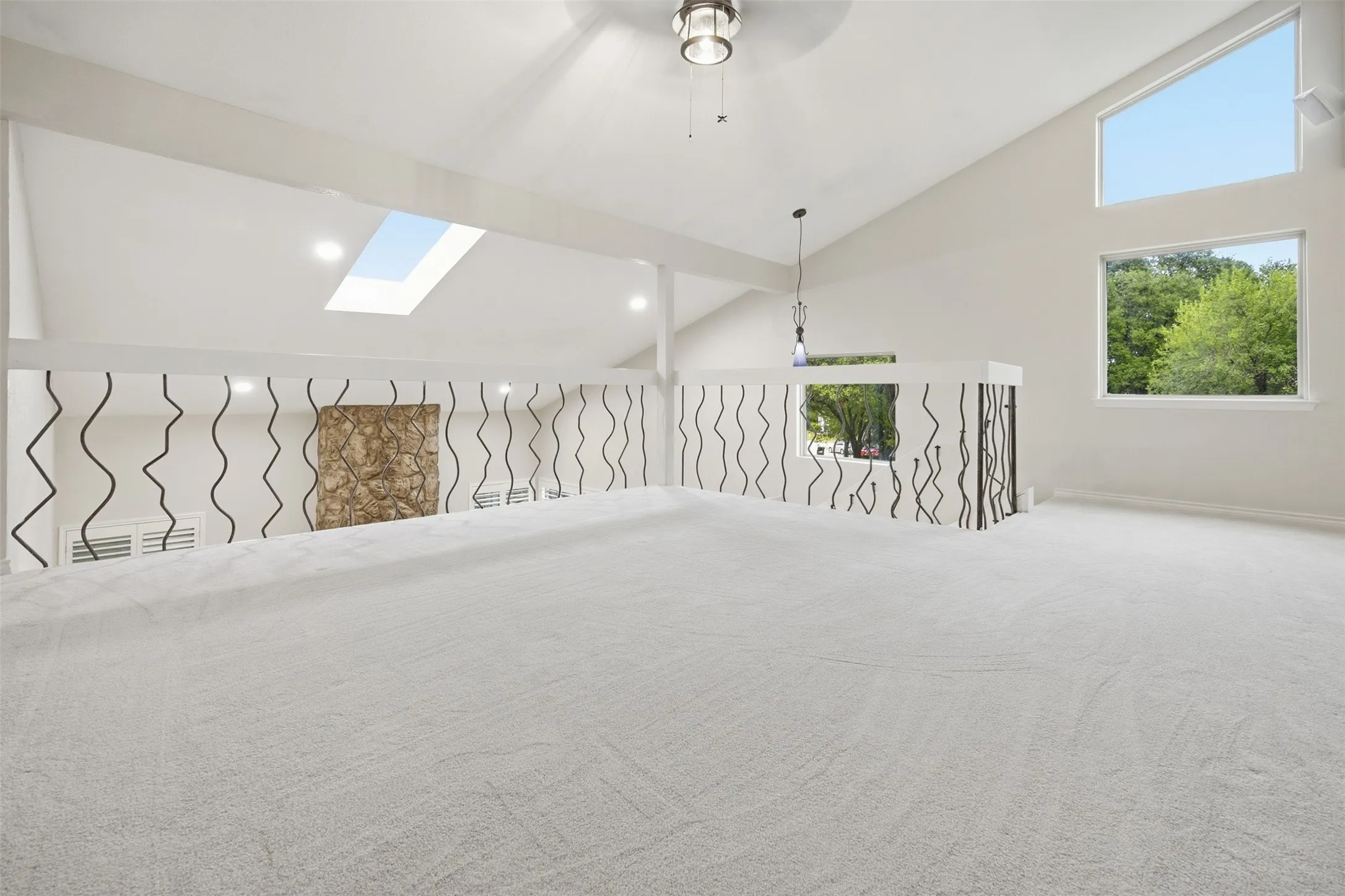 Vaulted ceilings with a skylight, recessed lighting, and a decorative railing