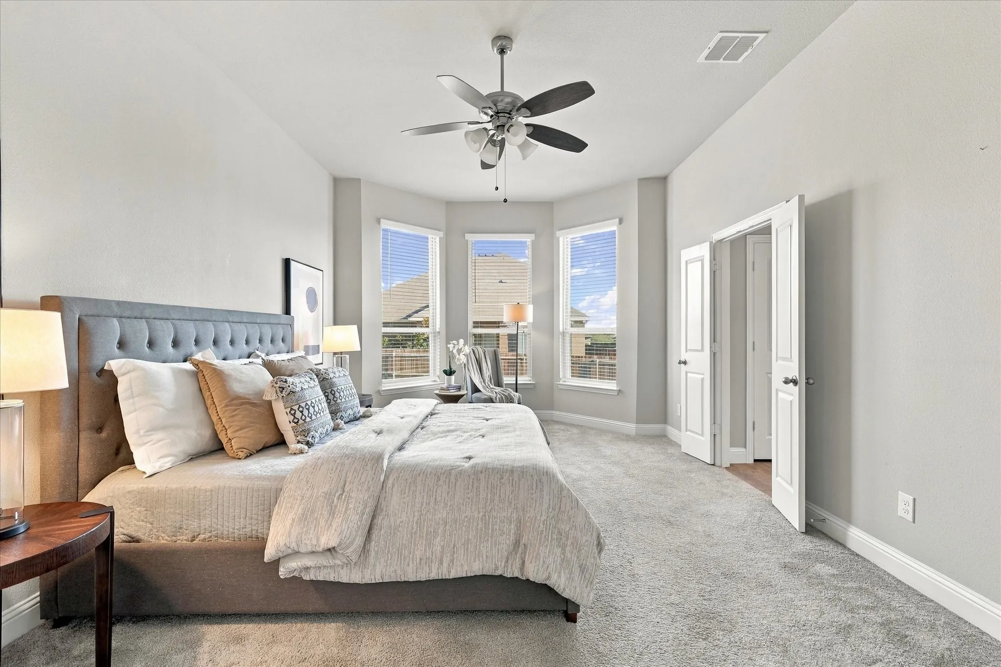High ceilings with a ceiling fan, bay windows with blinds, light-colored walls, carpeted flooring, and double doors