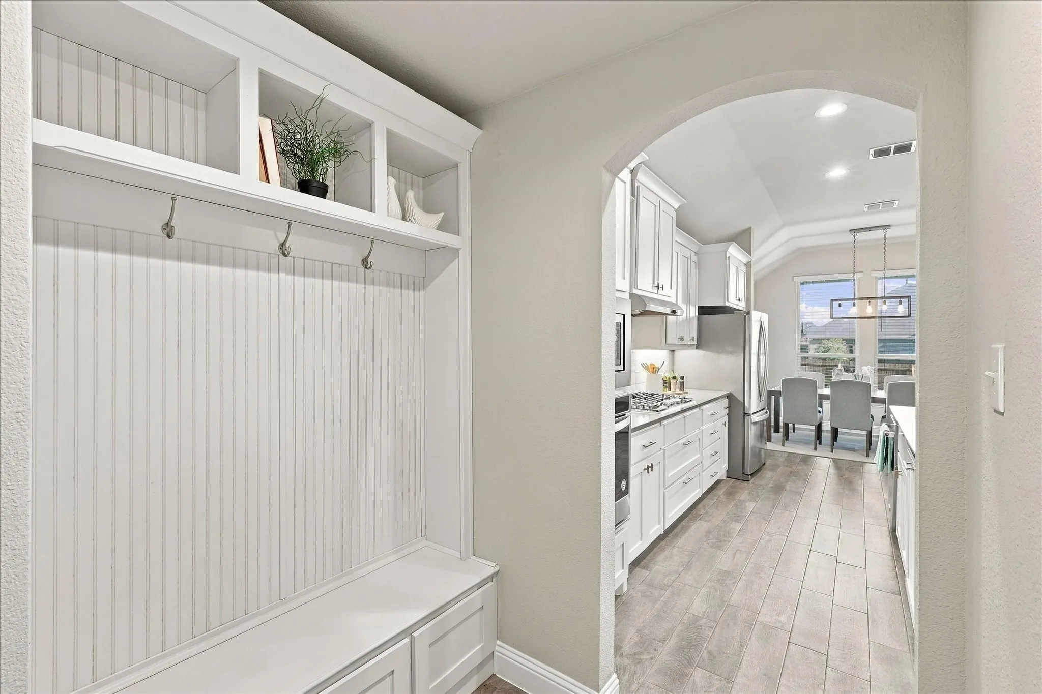 Built-in white mudroom bench with storage, overhead shelving, and coat hooks