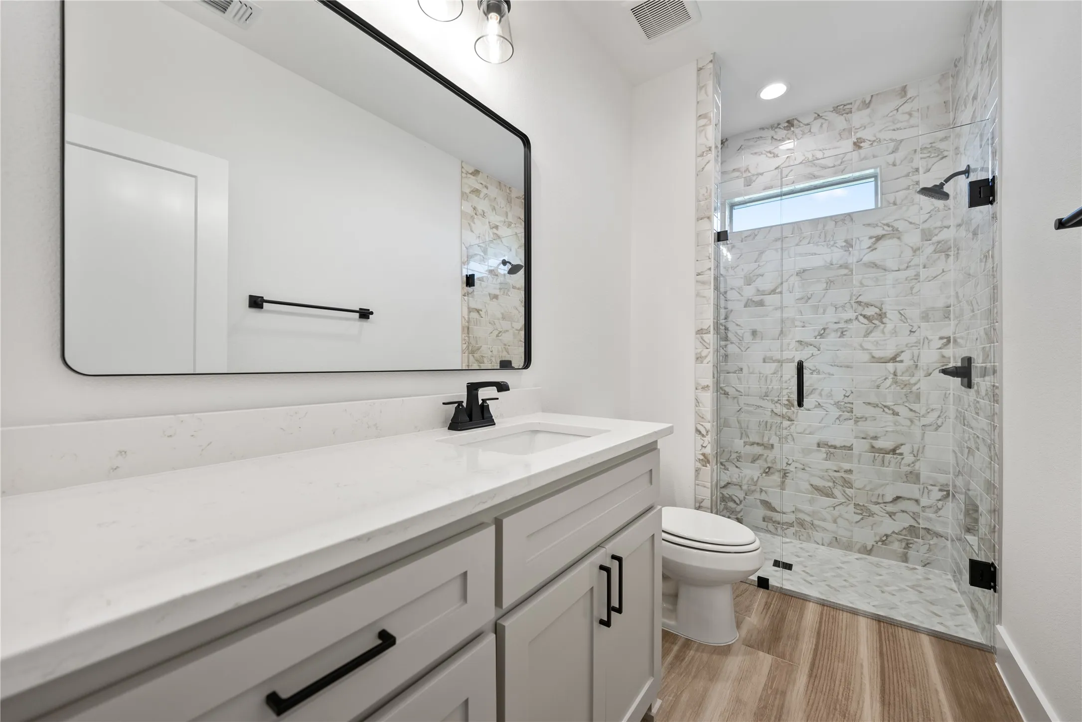 Shower with glass enclosure, white tile surround, and transom window