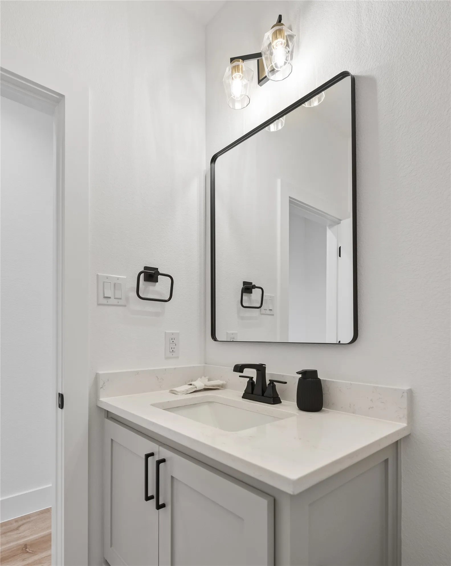 Vanity with light-toned countertop, undermount sink, matte black faucet, and light gray cabinetry
