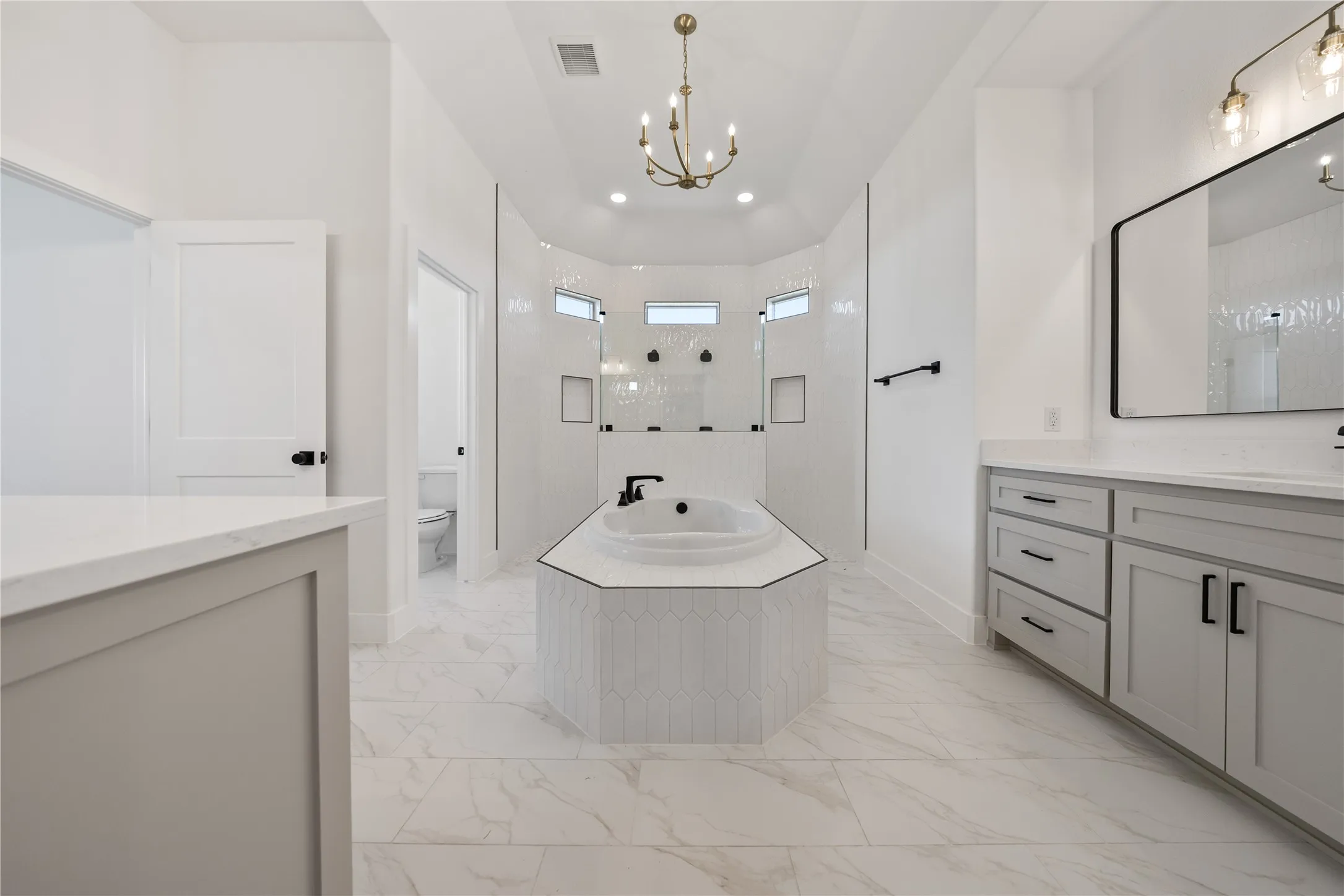 Spacious bath featuring a built-in soaking tub, dual vanity with undermount sinks, and a walk-in shower with tile surround