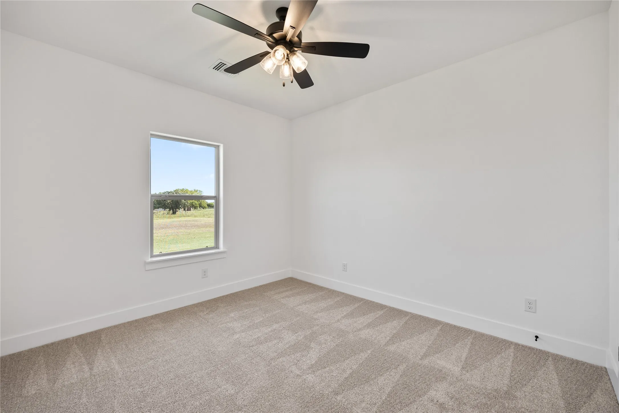 Neutral carpet flooring with a geometric pattern, single window, and a ceiling fan with integrated lighting