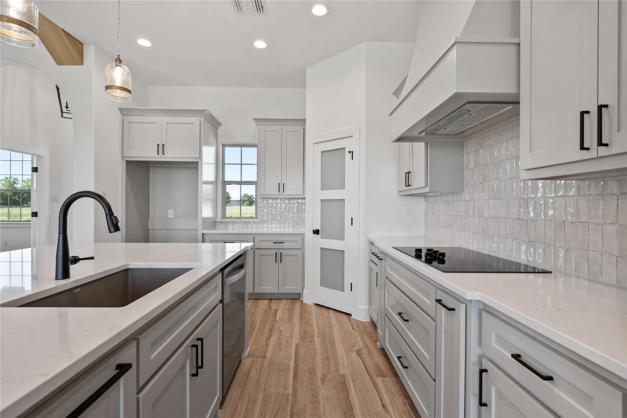 Kitchen featuring light cabinetry, quartz countertops, a matte black faucet, and a tile backsplash