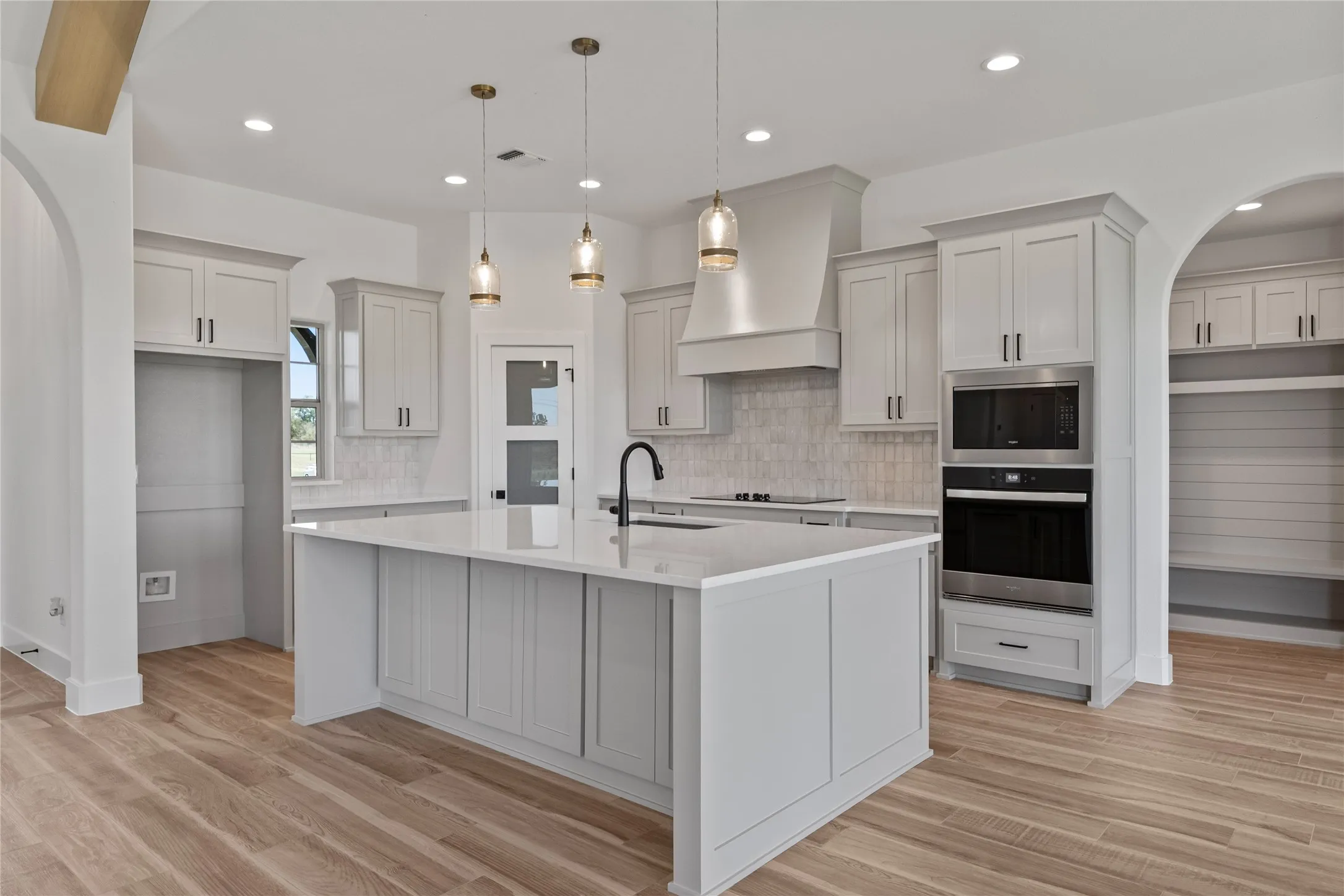 Kitchen featuring a central island with countertop, shaker-style cabinetry, wood-finish flooring, recessed lighting, and pendant light fixtures