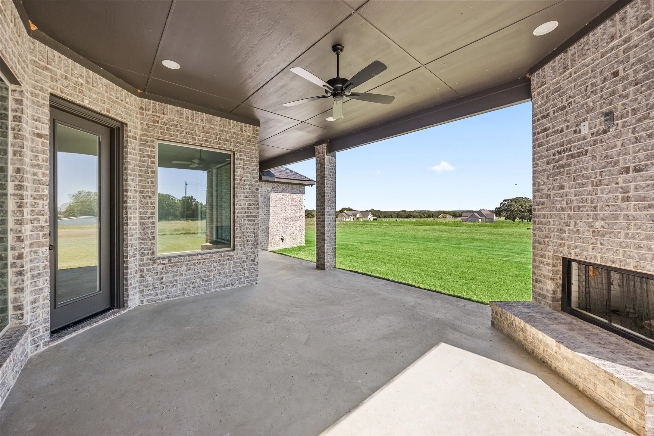 Expansive covered patio featuring a ceiling fan, recessed lighting, and a built-in outdoor fireplace