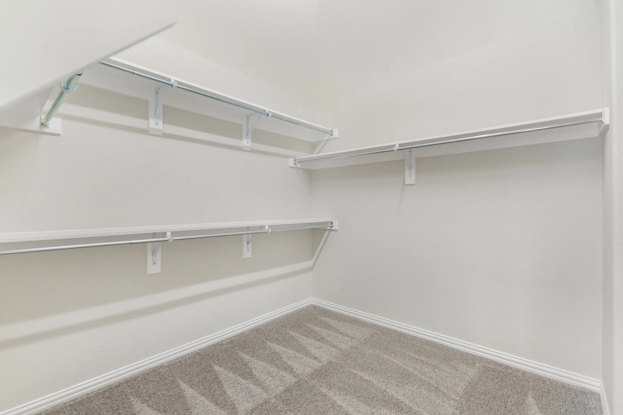Primary room. Built-in shelving with hanging rods and neutral tone carpeting